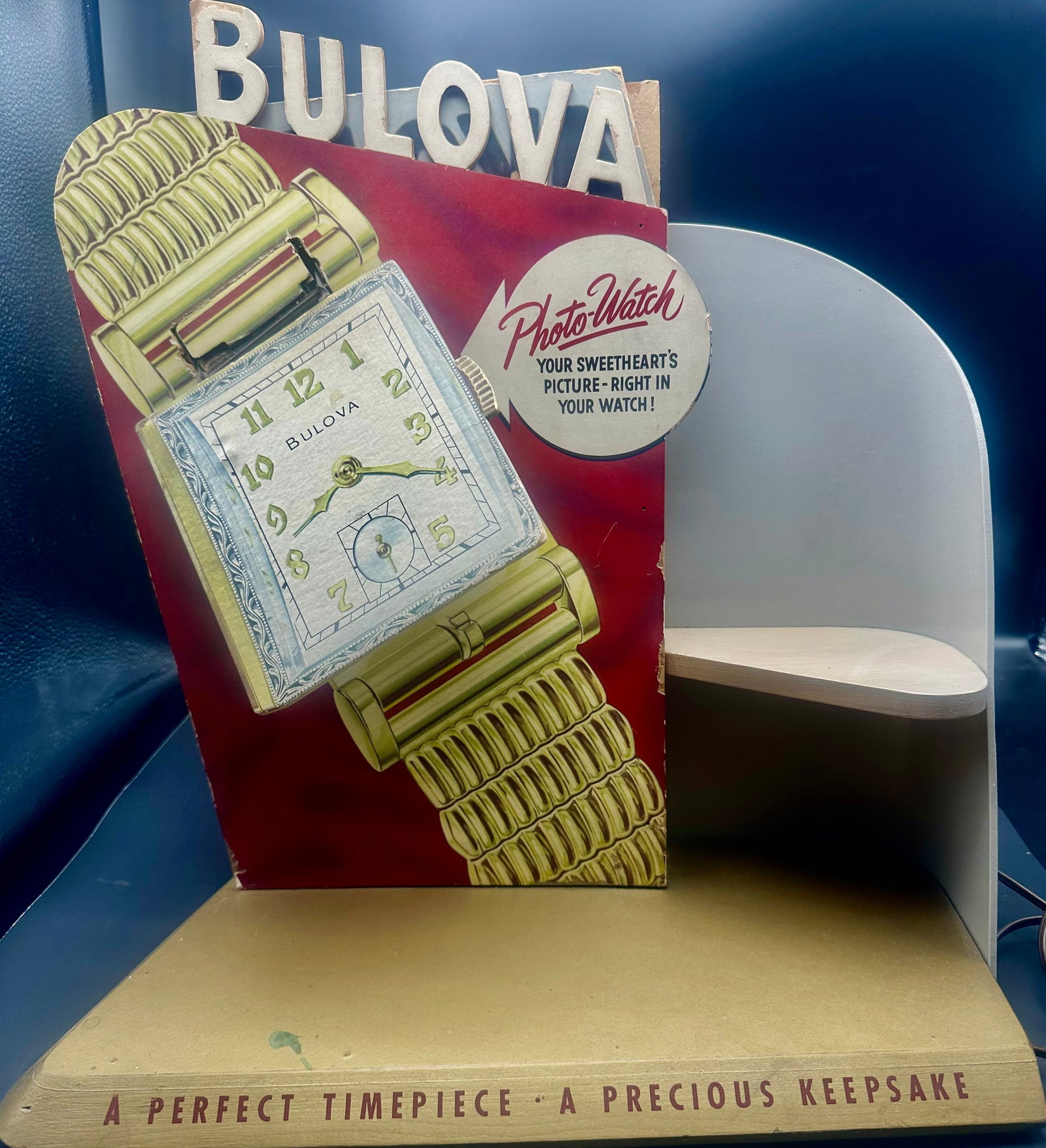 Vintage Bulova Photo-Watch Working Jeweler Advertising Display: Rare vintage Bulova countertop jeweler advertising display promoting the “Photo-Watch – Your Sweetheart’s Picture Right in Your Watch!” Features a large illustrated Bulova wristwatch, rais