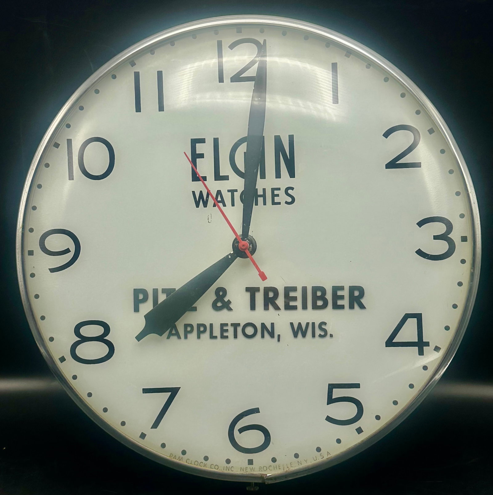 Vintage Elgin Watches PAM Advertising Wall Clock – Appleton WI – 15”: Vintage Elgin Watches jeweler advertising wall clock made by PAM Clock Co., New Rochelle, New York. Dial advertises Pitz & Treiber, Appleton, Wisconsin. Features a metal case, glass front, large Art D