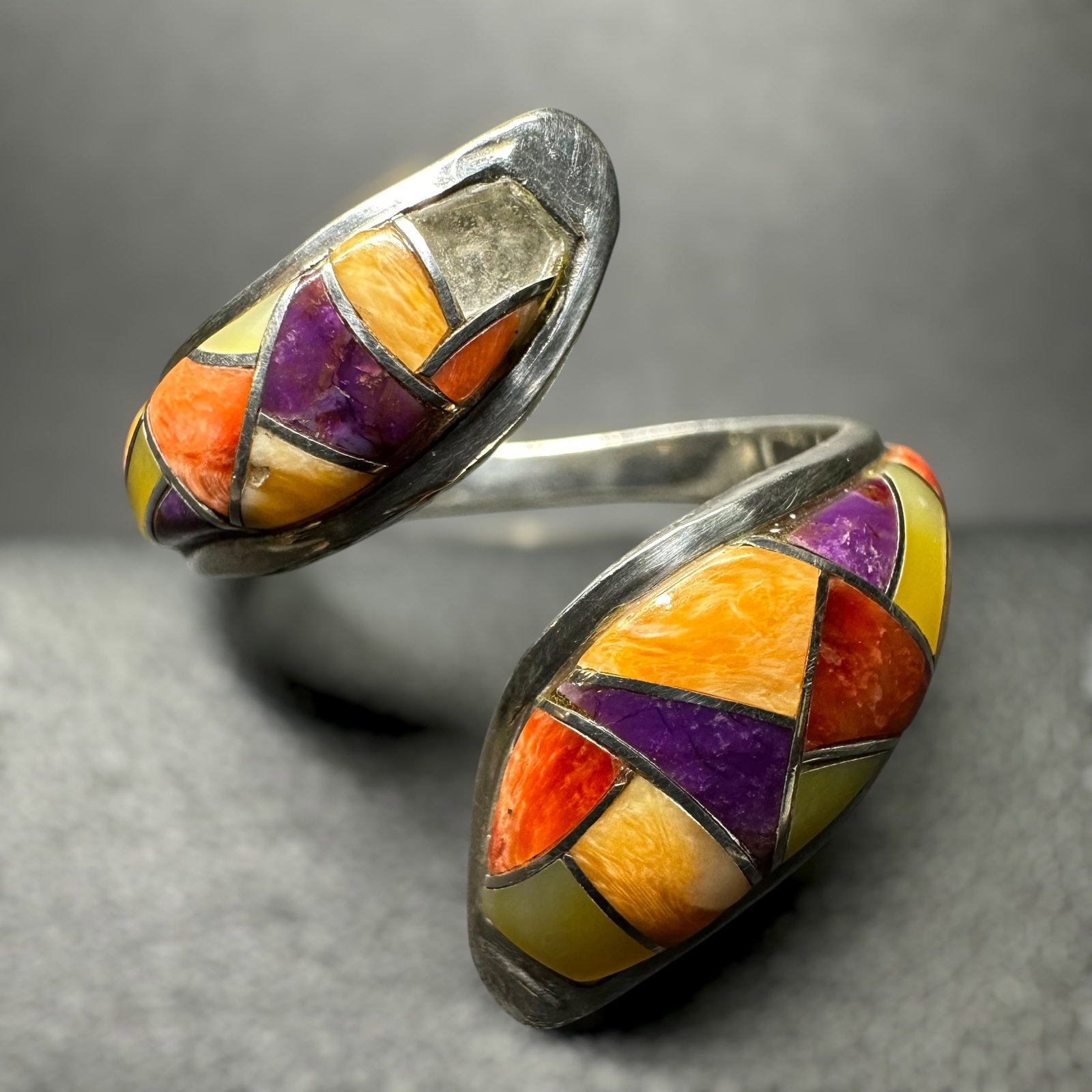 Sz7.5/6g Navajo (Diné) Sterling Silver Multi-Stone Inlay Bypass Ring: Sz7.5/6g Navajo (Diné) Sterling Silver Multi-Stone Inlay Bypass RingBrand/Model: “AG” hallmark. Unidentified artisan/shop.Manufacturer Location: Not marked.Year Produced: Unknown.Specs/Descri
