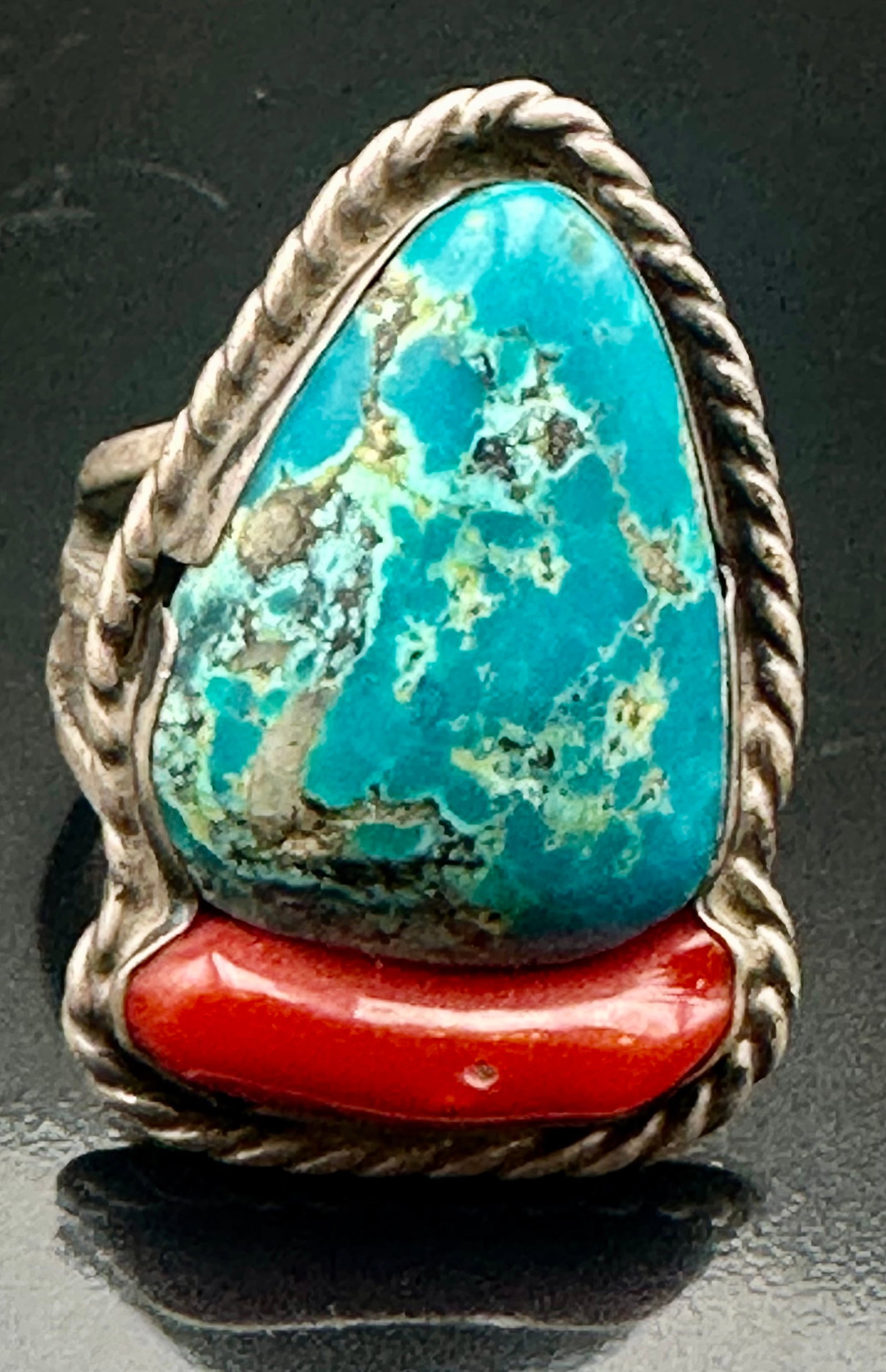20g Vintage Navajo Turquoise Coral Sterling Silver Ring: Vintage Navajo sterling silver ring with a large turquoise stone and red coral. Rope edge design with split shank. Nice old patina and wear. Weighs 20 grams.