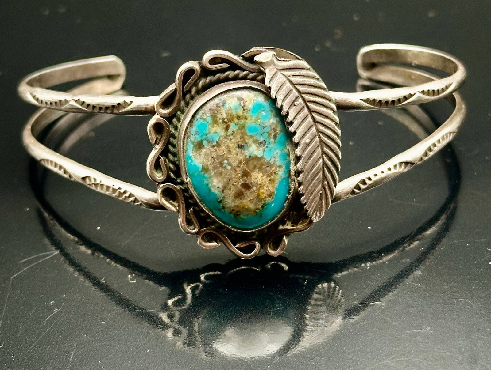 14g Vintage Navajo Sterling Silver Turquoise Leaf Cuff Bracelet: Vintage Navajo sterling silver cuff bracelet with a natural turquoise stone, silver leaf and twisted wire details. Split-band design with hand-stamped decoration. Unsigned. Shows vintage wear and tarn