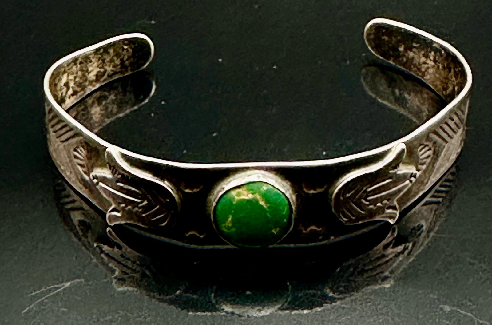 16g Vintage Navajo Sterling Silver Cerrillos Turquoise Thunderbird Cuff Bracelet: Vintage Navajo sterling silver cuff bracelet with a green turquoise stone and two applied thunderbirds. Hand-stamped design with a dark natural patina. Marked Sterling and unsigned. The turquoise appe