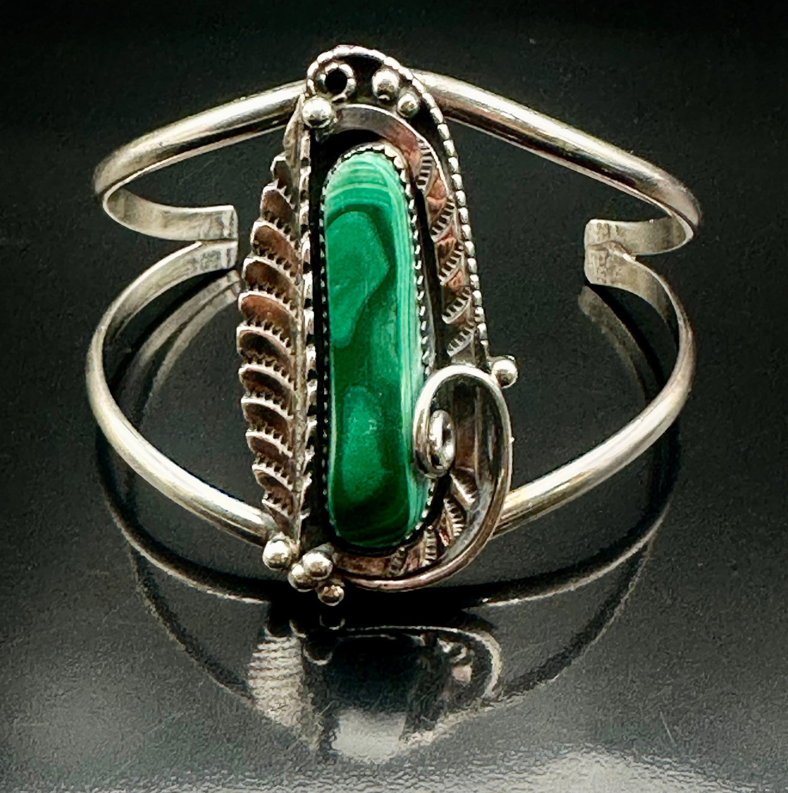 29g C. Secatero Navajo Sterling Silver Malachite Cuff Bracelet: Vintage Navajo sterling silver cuff bracelet signed C. Secatero. Features a long natural malachite stone with green banding and handmade leaf and scroll details. Weighs approximately 29g. Shows normal