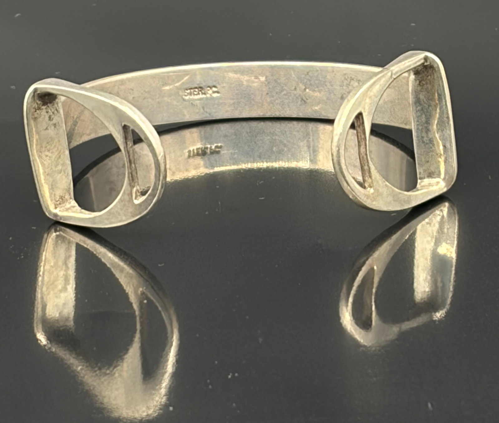 25.9 g Gorgeous Taxco Sterling Silver Bracelet: This striking vintage modernist cuff bracelet is crafted from solid sterling silver, featuring a sleek, minimalist band accented with bold, stylized equestrian stirrup terminals at each opening.