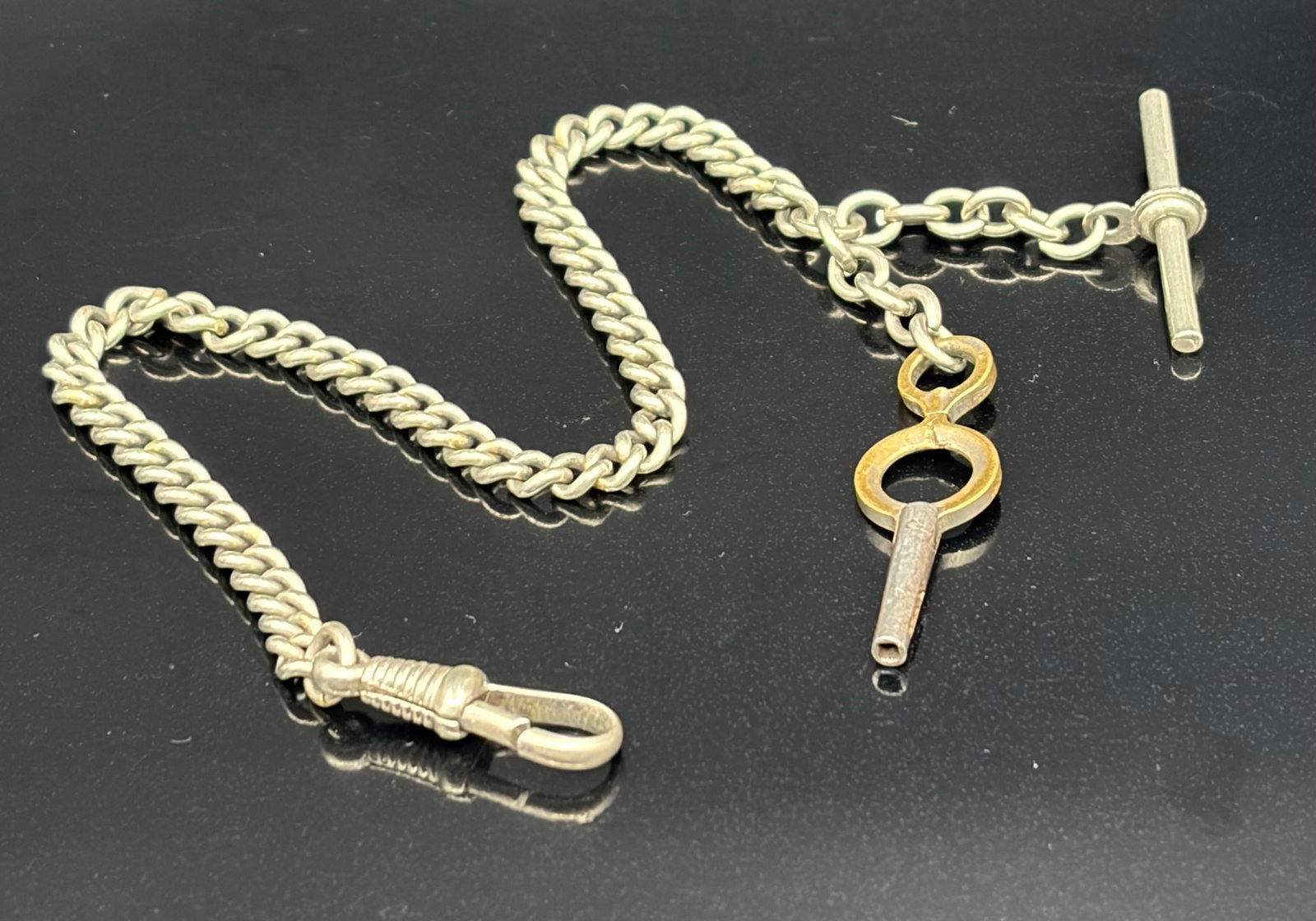 16.7 g Antique Curb-Link Single Albert Pocket Watch Chain with Watch Winding Key & T-Bar: This is an authentic antique single Albert pocket watch chain featuring a classic curb-link style. The piece showcases a two-tone appearance, pairing a silver-toned metal chain with an integrated gold