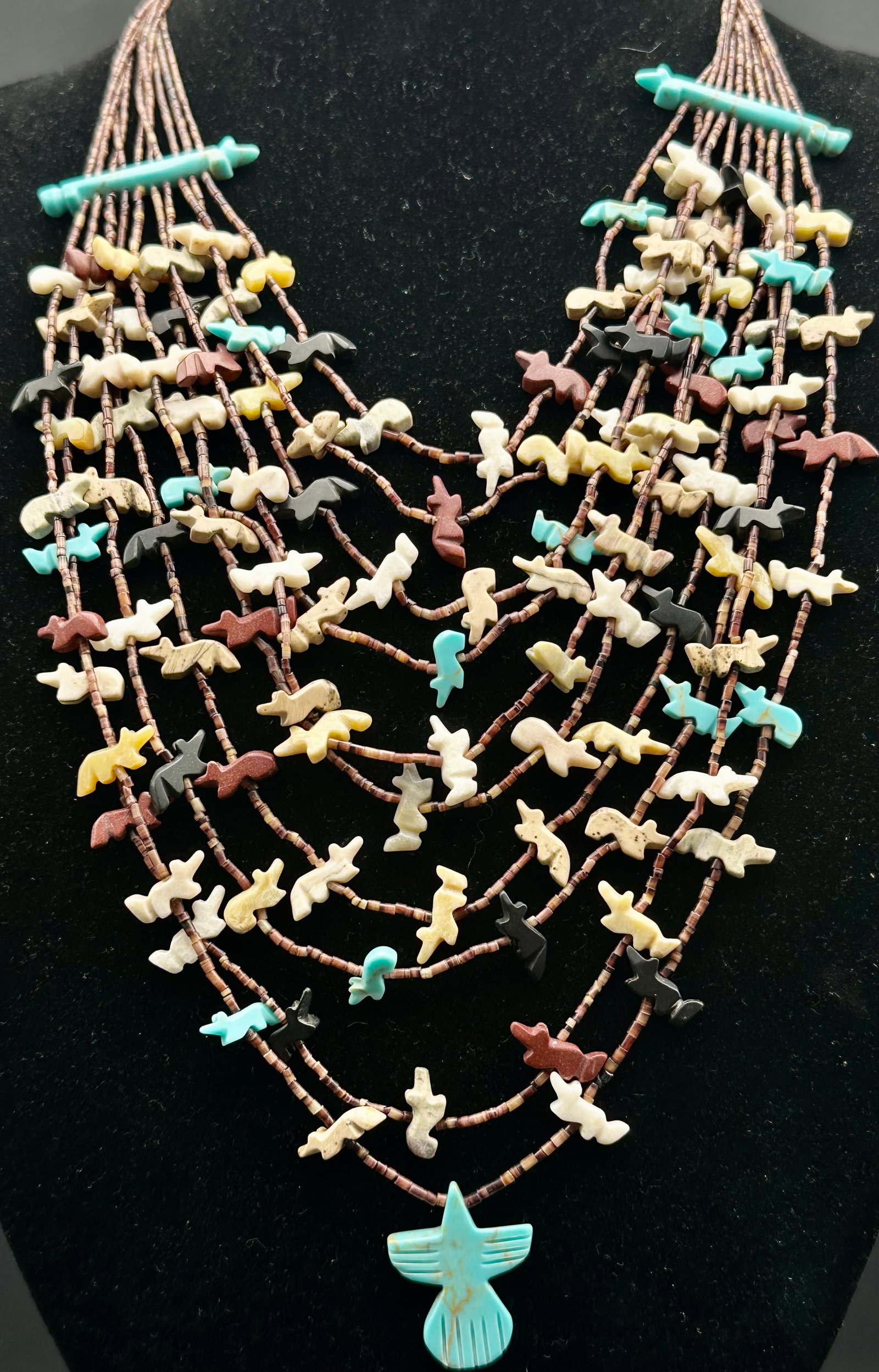 42g Vintage Zuni Pueblo 10-Strand Fetish Necklace Turquoise Thunderbird: Vintage Pueblo Native American 10-strand fetish necklace, likely Zuni or Kewa. Made with shell heishi beads and many carved stone animals in different colors. Features turquoise spacer bars and a larg