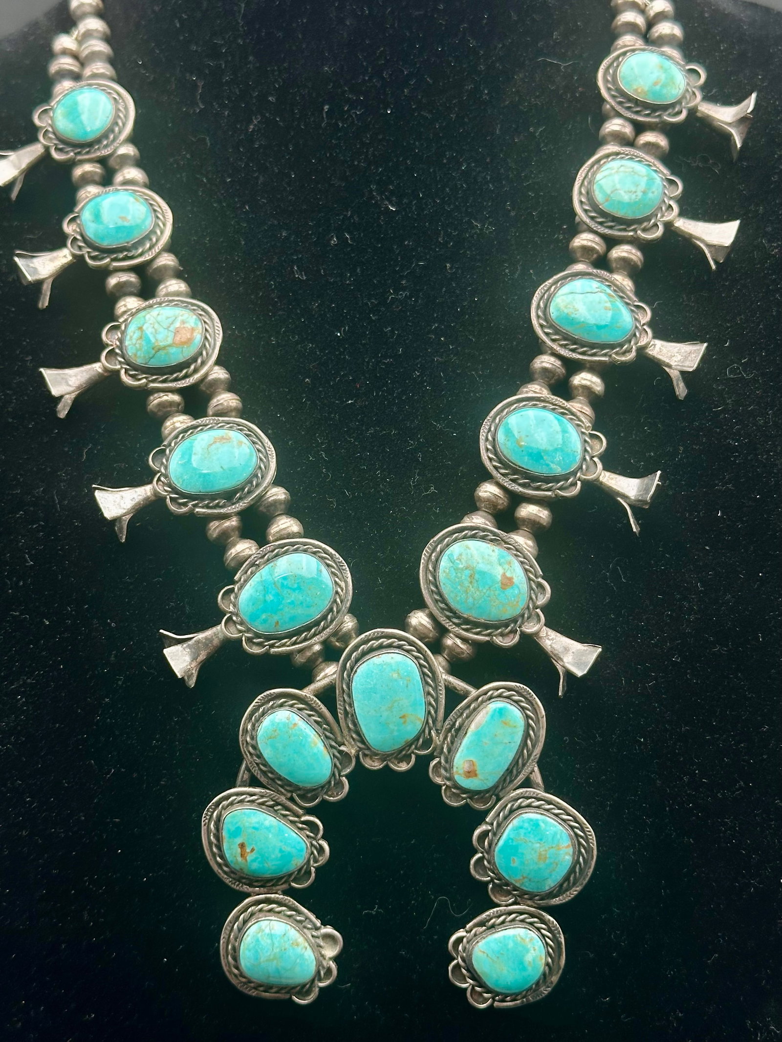171g Vintage Navajo Sterling Silver Turquoise Squash Blossom Necklace: Vintage Navajo sterling silver squash blossom necklace with 17 turquoise stones. Made with two strands of handmade silver beads, side blossoms, and a large naja centerpiece. Nice old patina and natura