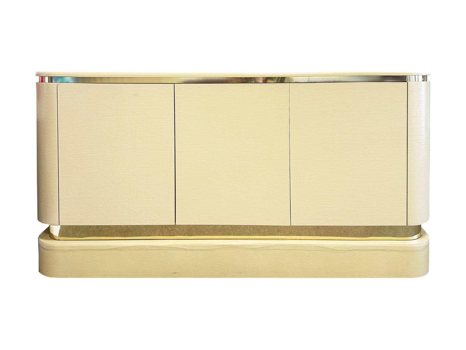 Karl Springer Style Credenza Sideboard: 1980s custom built sideboard or credenza in the style of Karl Springer. Heavy wooden credenza covered in linen and lacquered with brass tone accents. Unmarked. Cabinet sits on pedestal base. 