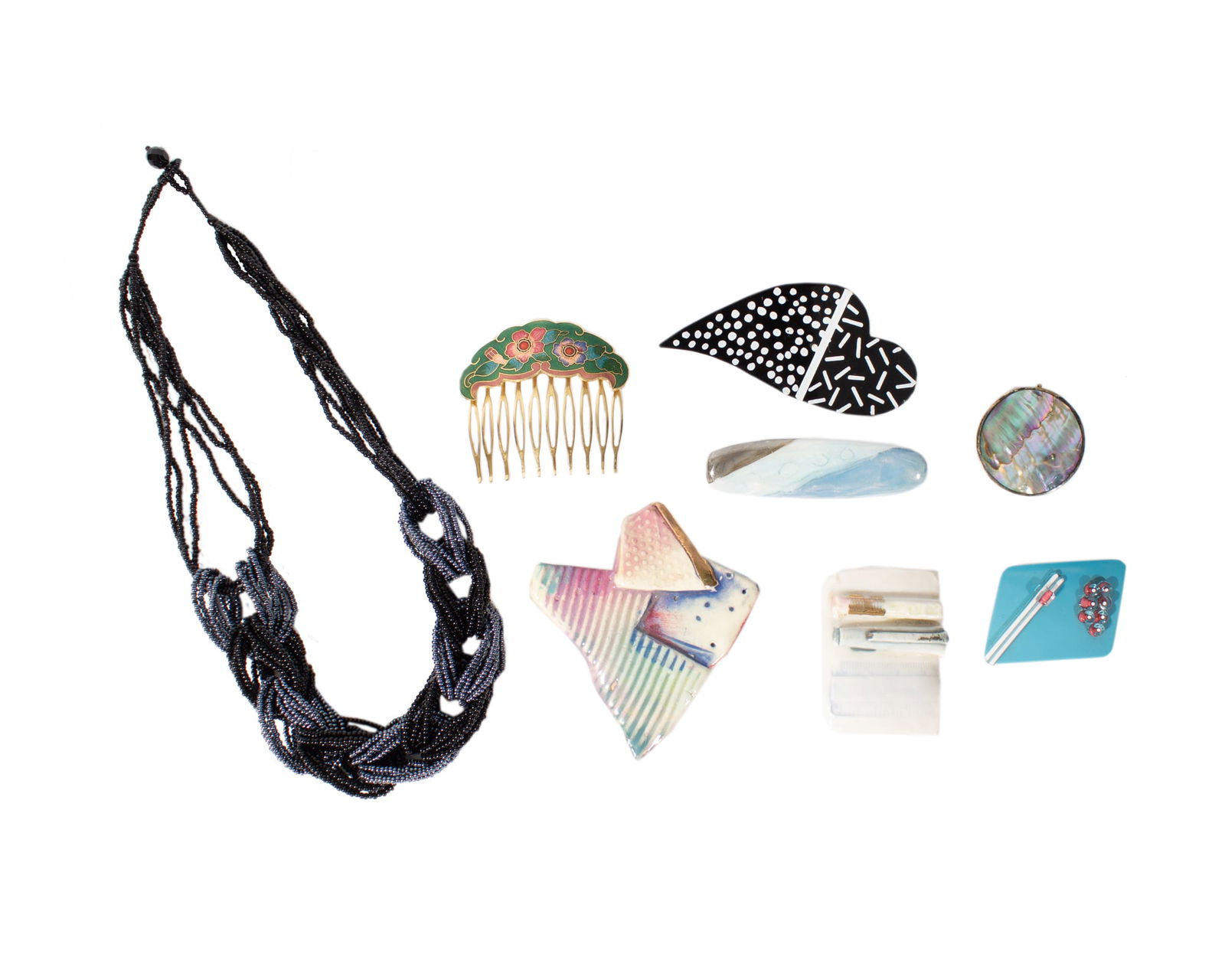 Costume Jewelry: Group of costume jewelry. Included are three ceramic pins, a glass pin, a metal heart pin, a Mexican metal pendant brooch, a cloisonne comb, and a beaded necklace. Measurements: 19.5" W (n