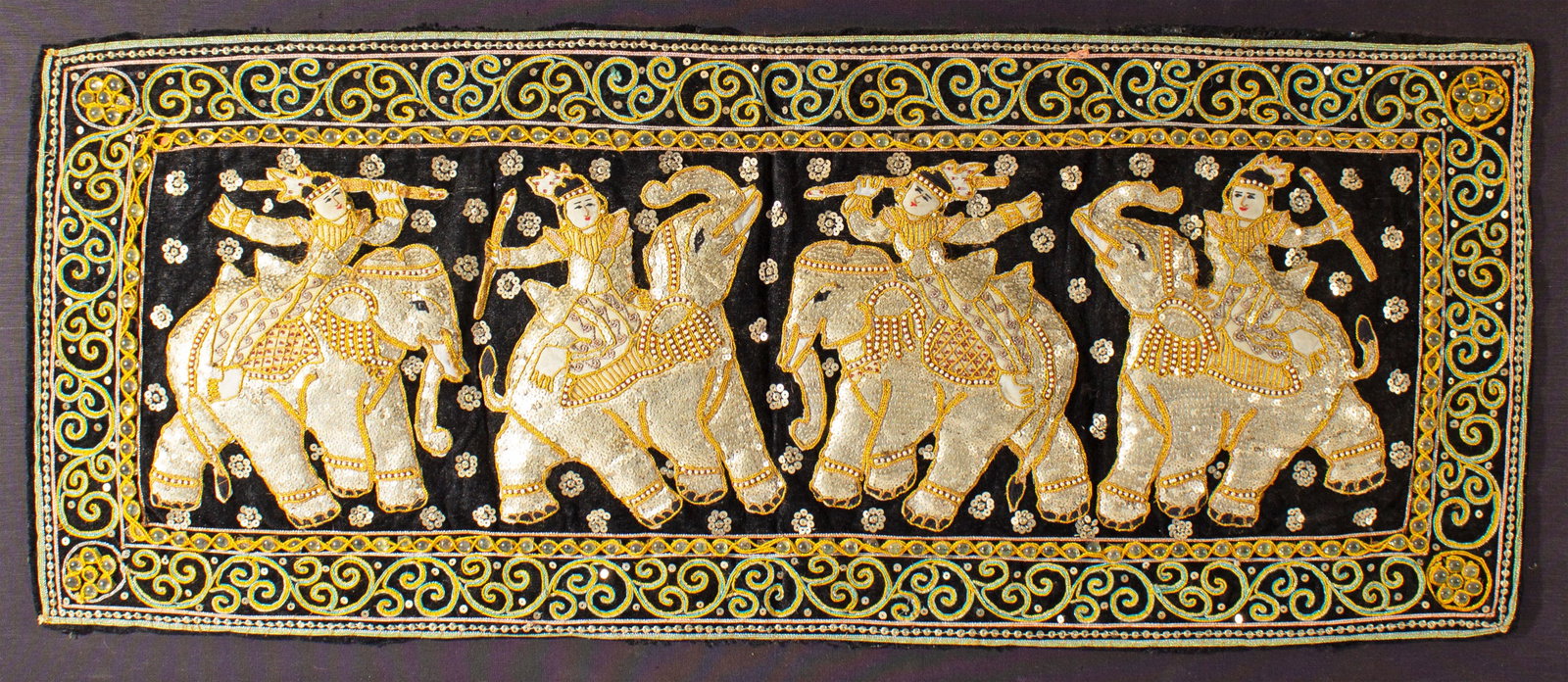 Burmese Kalaga Tapestry: Framed Burmese Kalaga tapestry depicting figures riding elephants. Unmarked. Measurements: 46.5" W x 22.75" H x 1.25" D (frame); 38.25" W x 16.5" H (tapestry). I