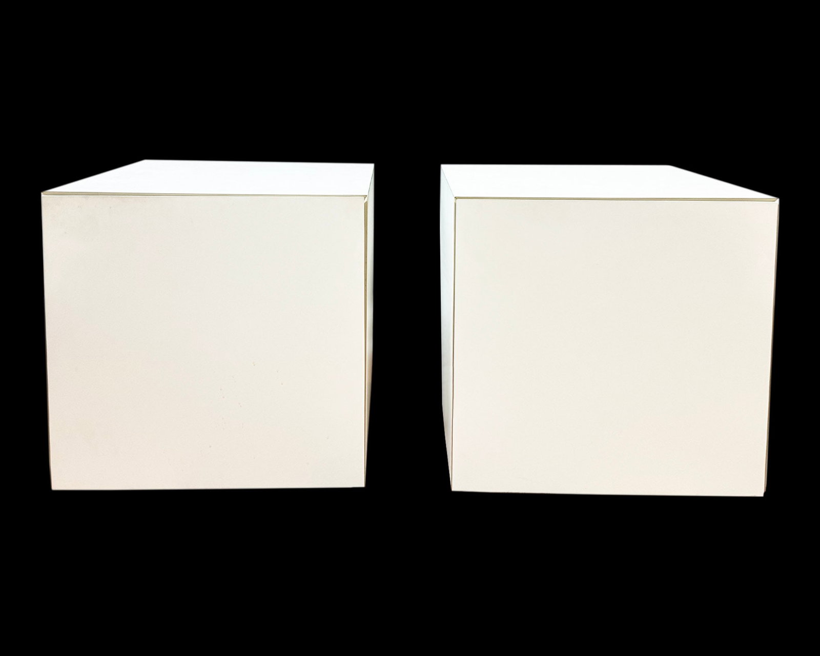 White Laminate Nightstands: Pair of cube-shaped white laminate nightstands. Unmarked. Measurements: 18.5" W x 18.5" H x 18.75" D. Pickup or third party shipping required.