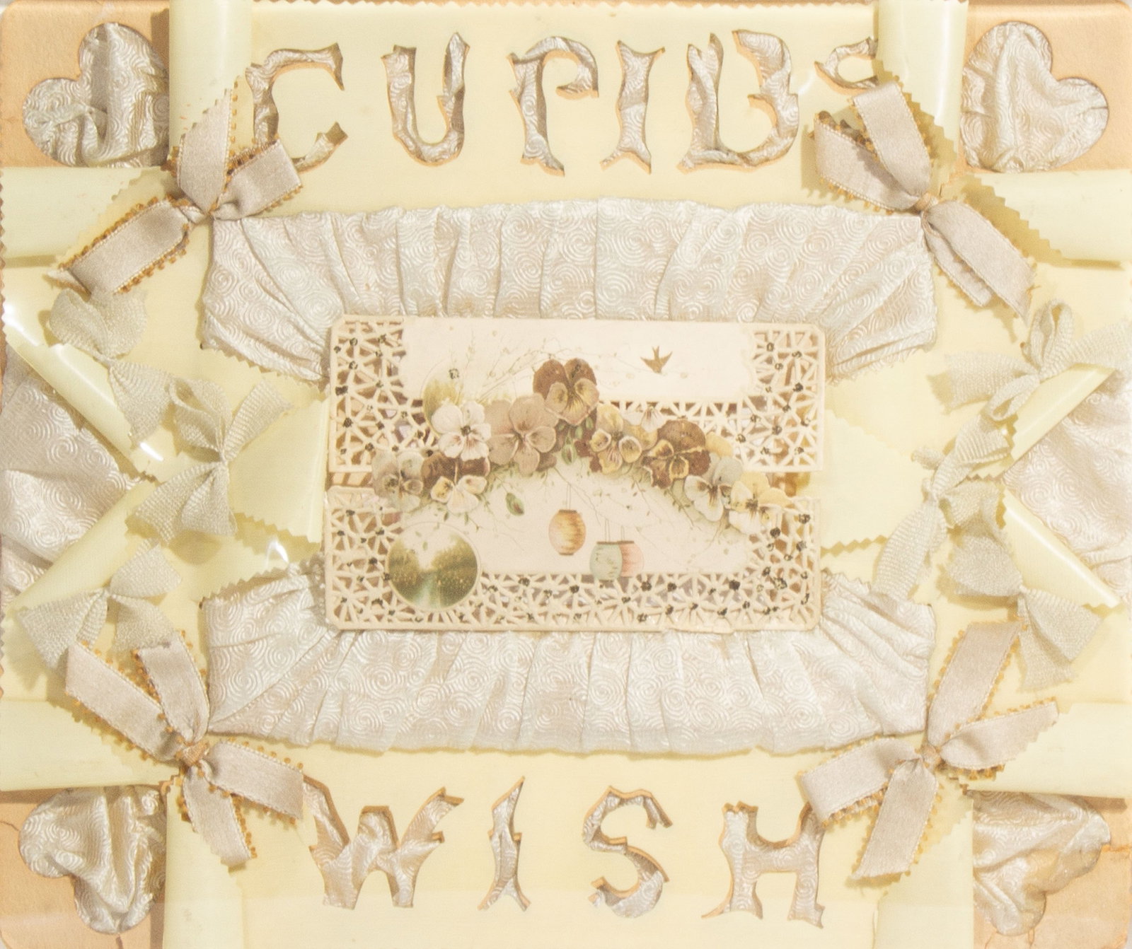 Antique Victorian "Cupids Wish" Die Cut Greeting Card: Elaborate antique Victorian die cut greeting card mounted with ribbon and fabric. Reads "Cupids Wish". Displayed in acrylic box. Measurements: 12.25" W x 10.5" H x 2" D