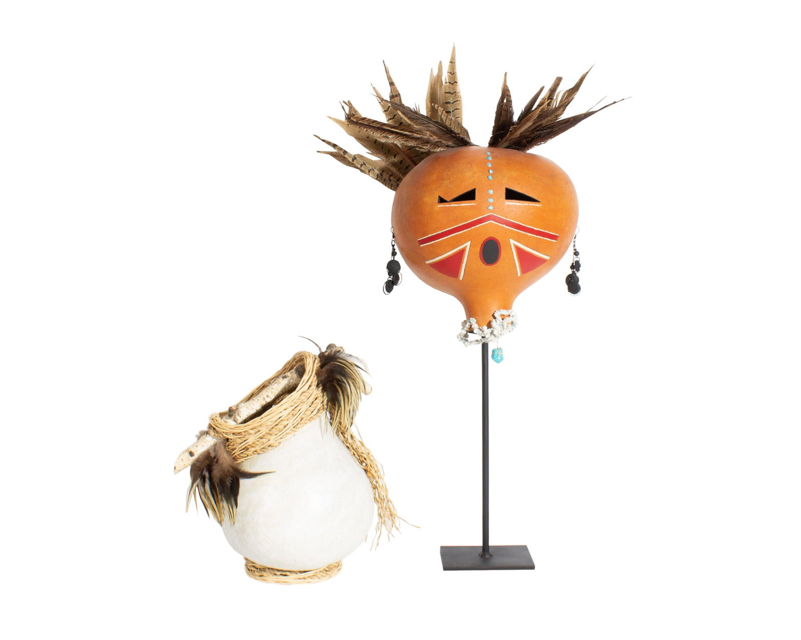 Bonnie E. 1999 Gourd Basket and Gourd Sculpture: 1999 basket or vase made from a gourd. Gourd has stick handle with woven elements at top and feather, wooden bead, and dried grass accents. Dated and signed "Bonnie E." to underside. Also in