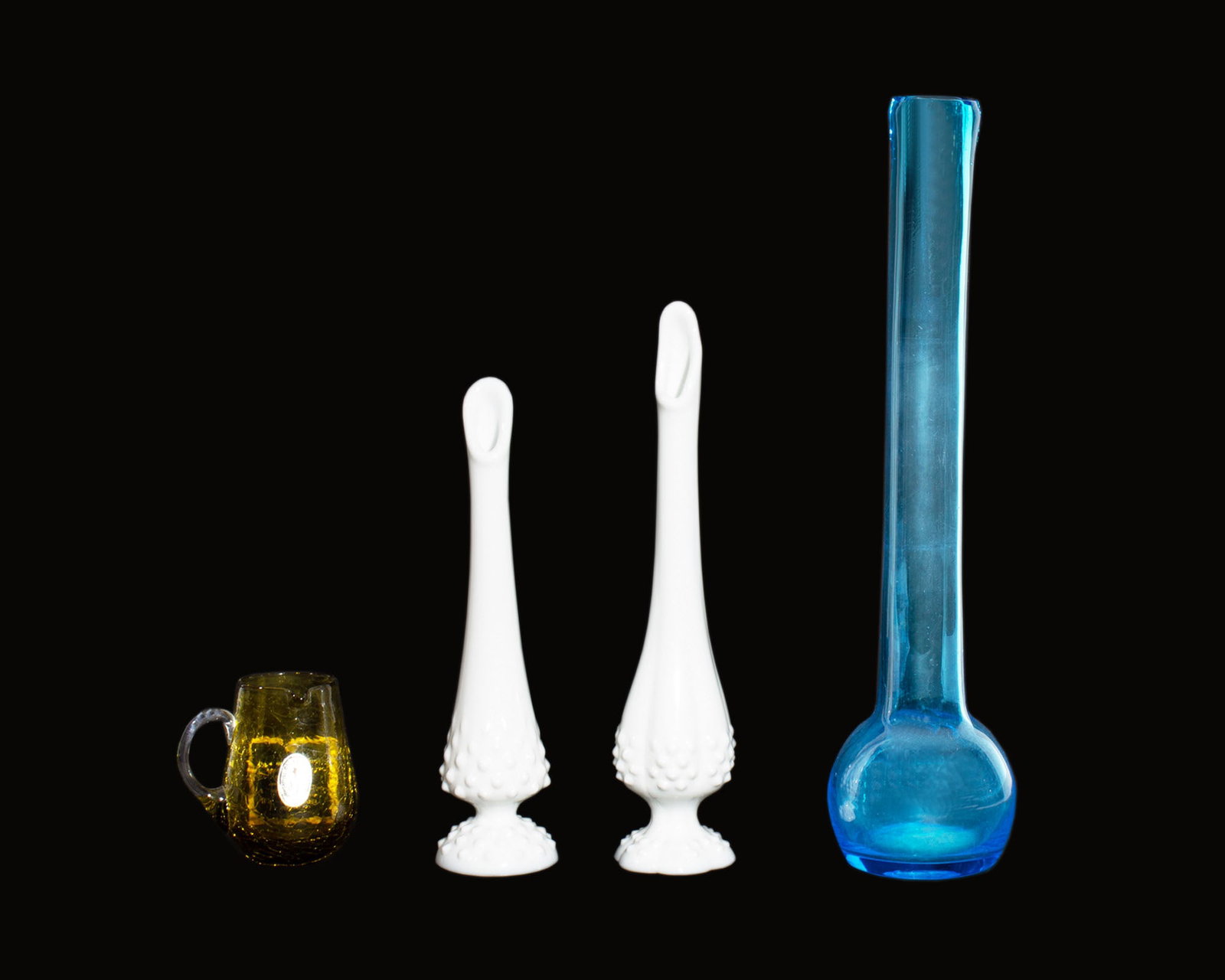 Mid-Century Pilgrim, Bischoff, Fenton Glass: Group of four mid-century glass items. Included is a blue Bischoff glass vase, a Pilgrim crackle glass creamer/pitcher, and two Fenton milk glass hobnail bud vases. Measurements: 3.5" W x