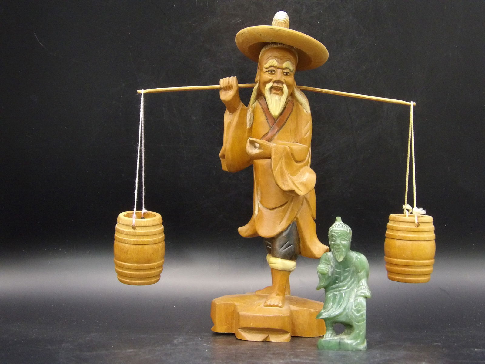 Japanese Wooden Carving Of Man Carrying Water Buckets and Nephrite Jade Man Statue: Lot of 2. Wooden carving is 7.8 inches height. Nephrite jade statue is 2.8 inches height.