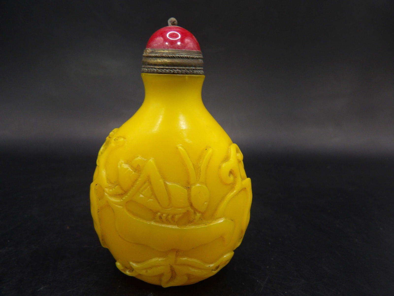 Chinese egg yolk color glass snuff bottle with raised motif and Qing dynasty Qianlong mark: 2.6 inches height.