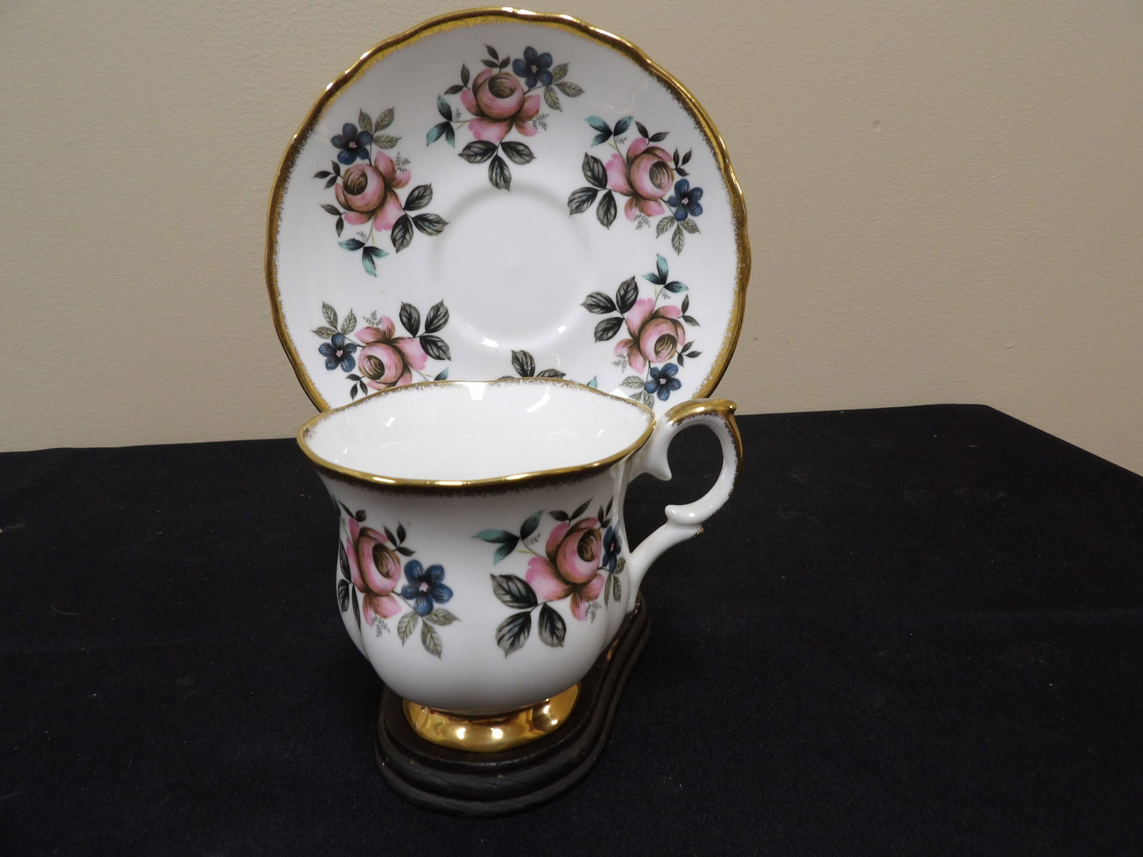 Staffordshire England bone China cup and saucer with gold rim on wooden stand: Saucer is 5.6 inches diameter.