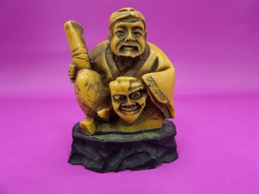 antique Japanese resin netsuke depicting a man holding a face mask on custom base