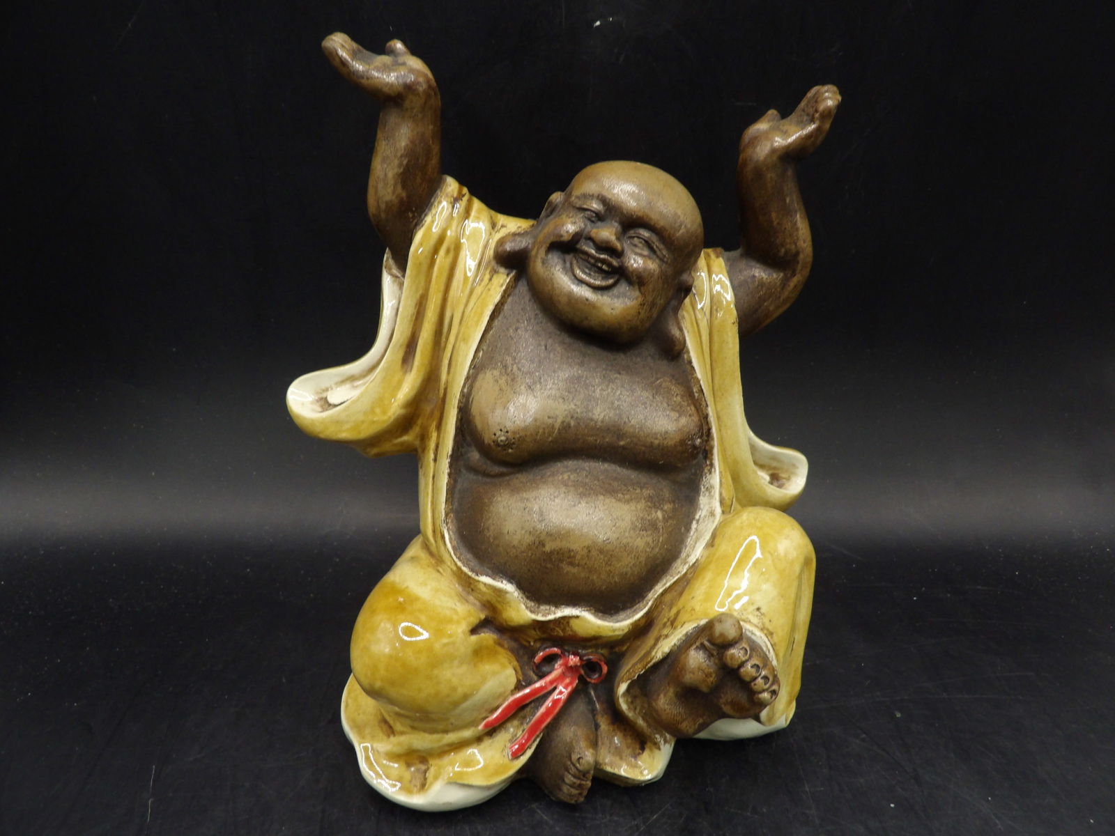 glazed Chinese ceramic figurine of a laughing buddha with raised hands (1 of 6)