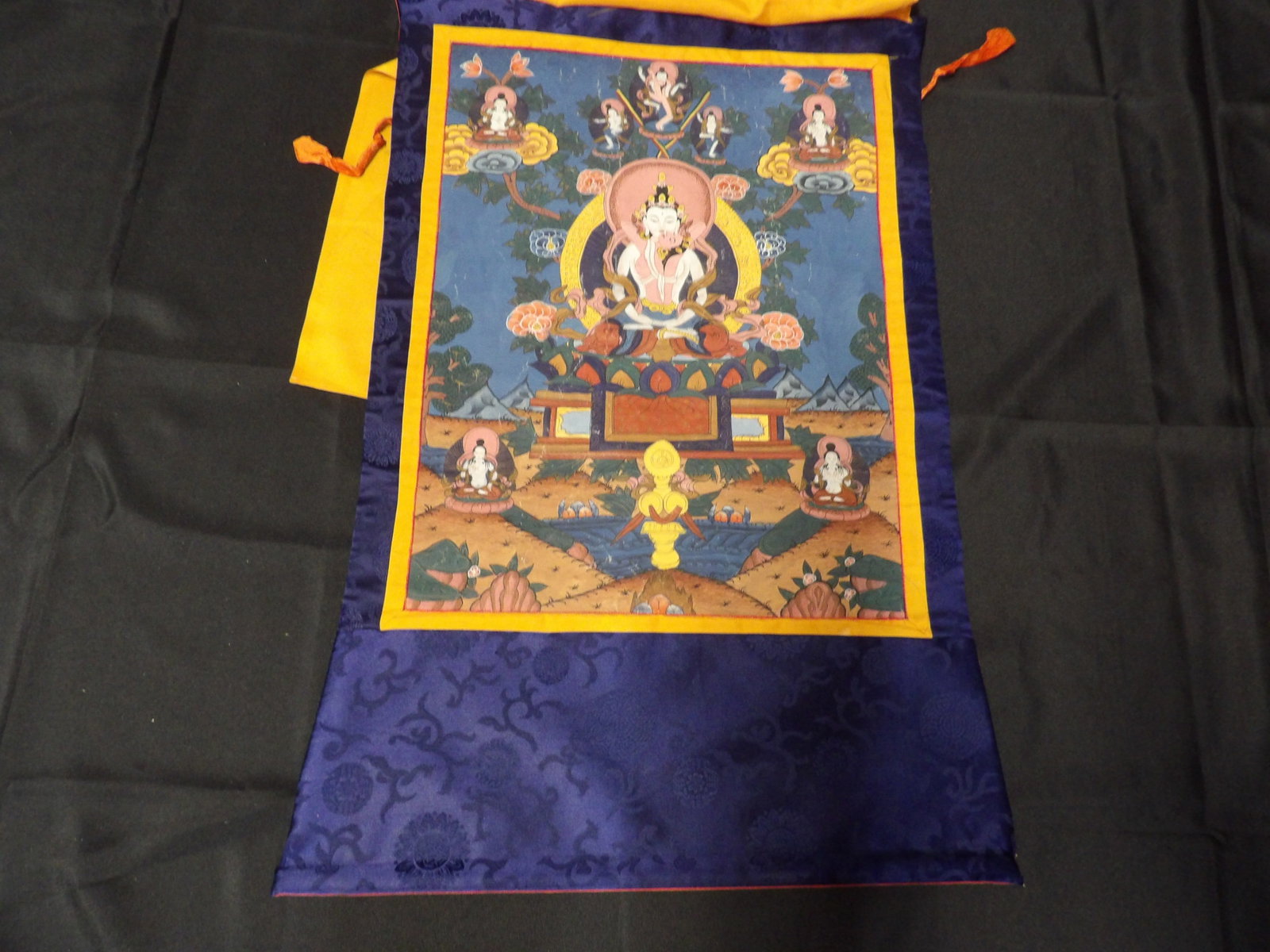 19th/20th century hand painted Tibetan Buddhist Thangka with silk cover and hanging pole: Depicting a deity and surrounding figures. Thangka painting area is 20.5 inches height. Entire Thangka is 31 inches height.