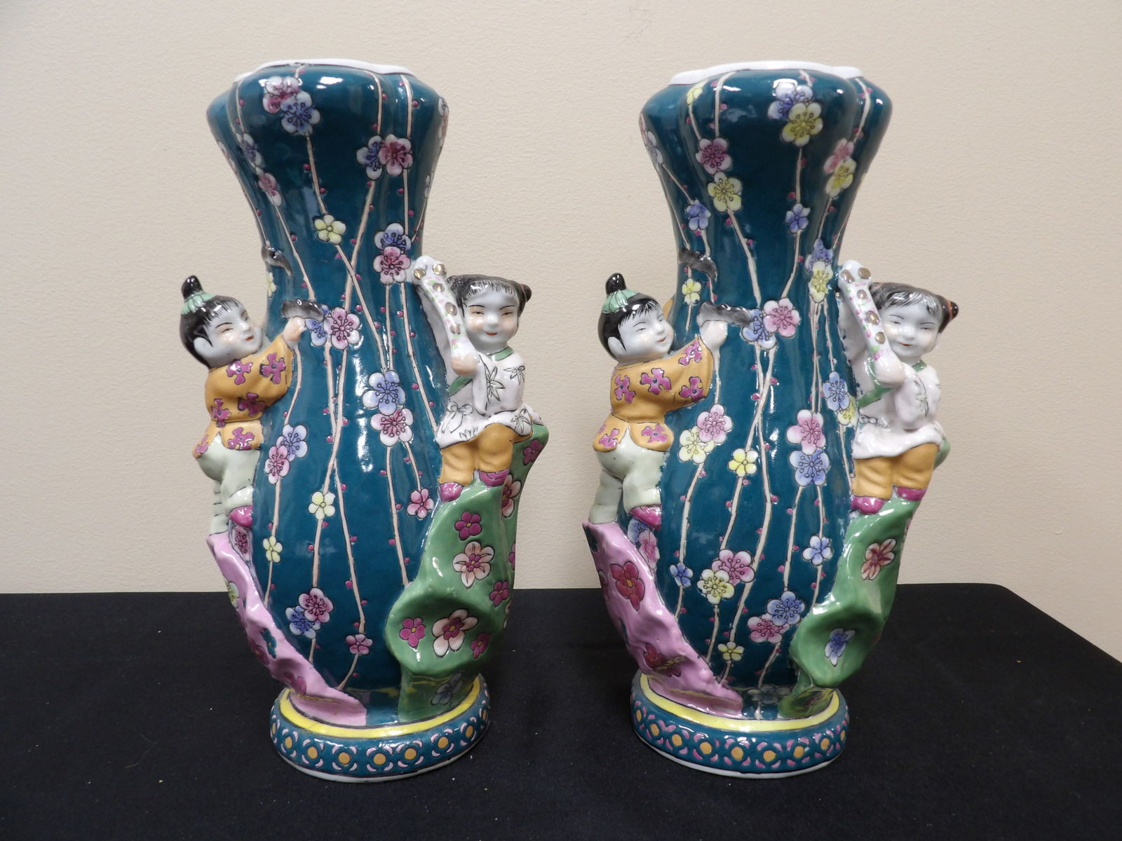 pair of Chinese porcelain vases with children climbing floral motifs and Qing dynasty Qianlong mark: 11 inches height.