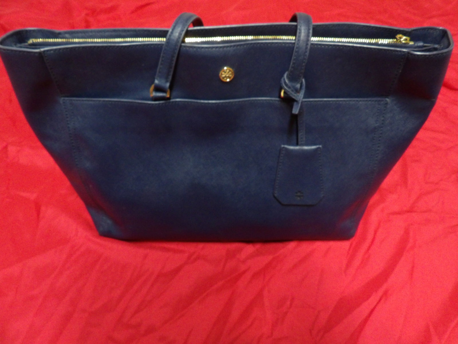 Tory Burch navy blue Saffiano leather tote bag with multiple compartments and gold hardware: Bottom width is about 15 inches. Front and back have large pockets. Inside multiple pockets and compartments including laptop area.
