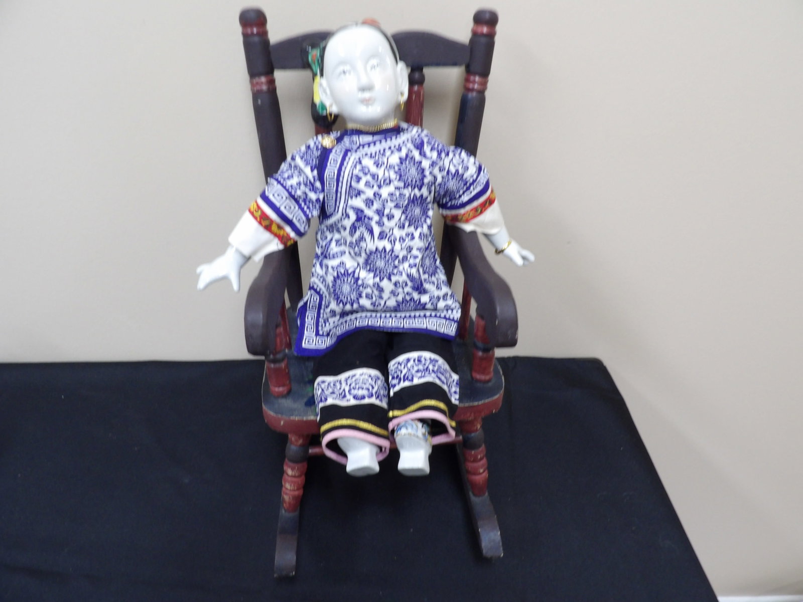 Chinese porcelain doll in traditional attire seated in wooden rocking chair: Rocking chair is approx. 16 inches height. Doll has porcelain face, hands and shoes. We will inhouse ship items to you very affordable and efficient. Select self-arrange shipping.