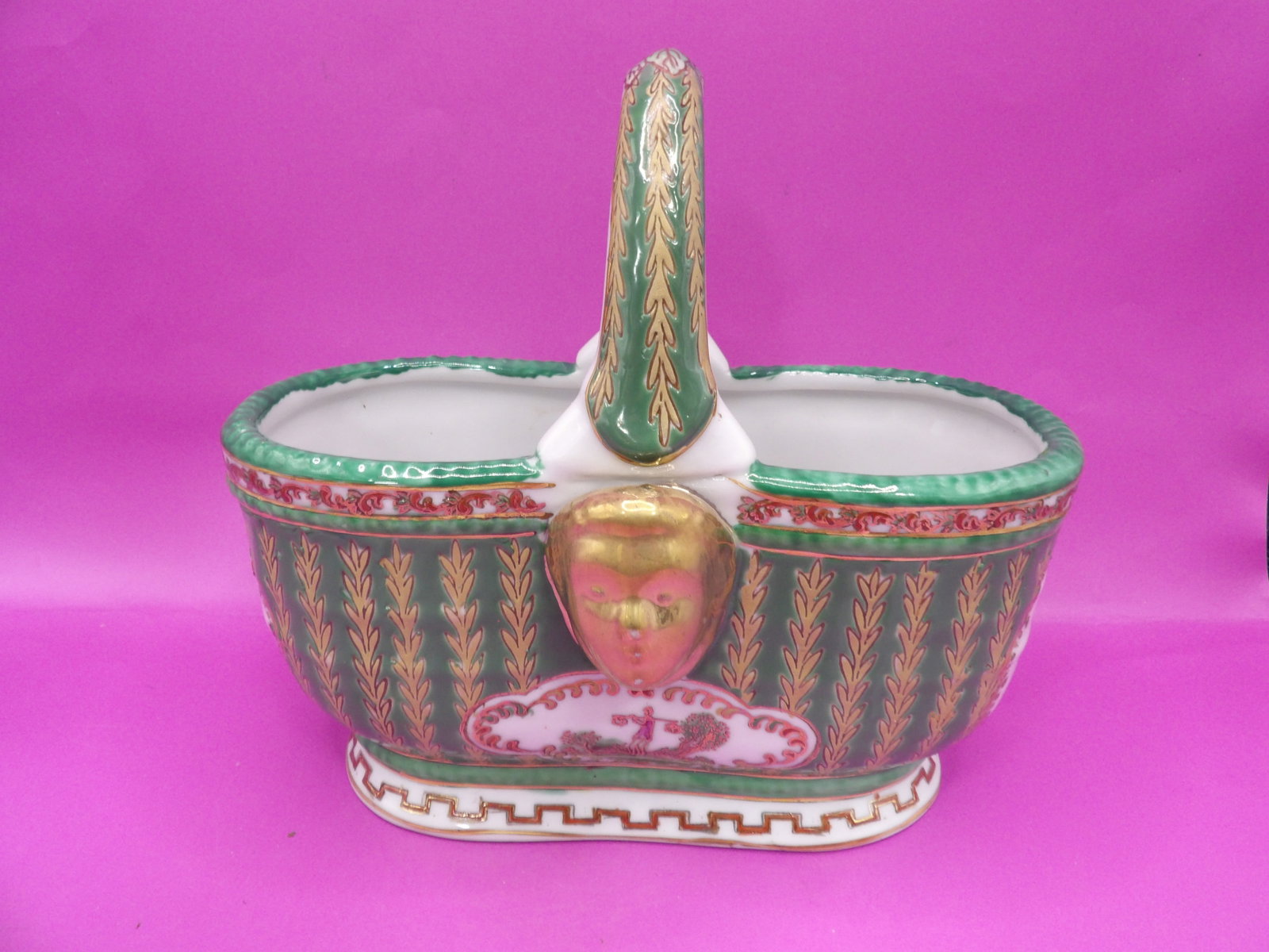 Chinese porcelain decorative basket with gilded face motif and chinoiserie-style painting: 7.5 inches length.