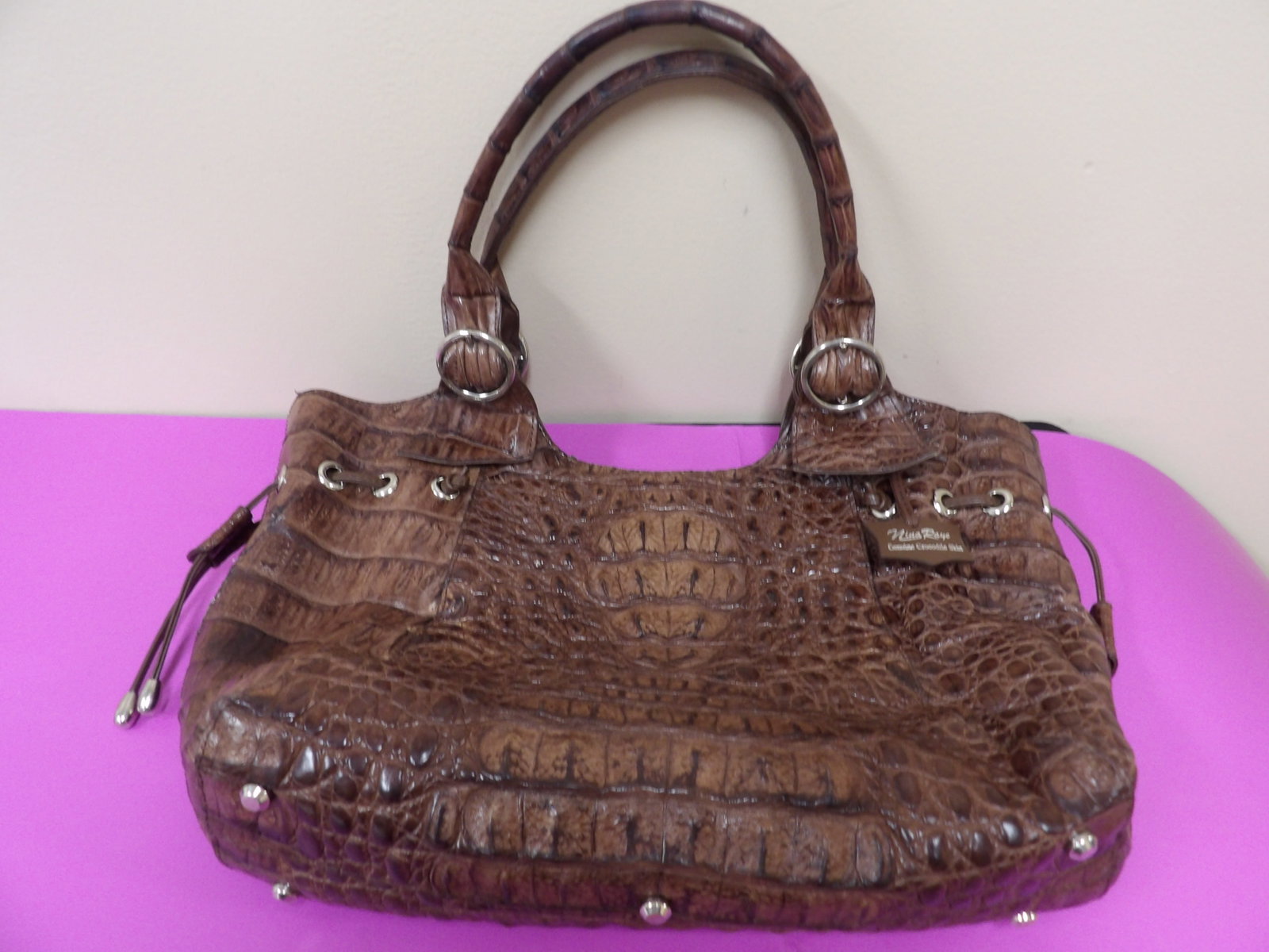 Nina Rayle genuine crocodile skin handbag marked: 12.5 bottom length. 16 inches top length. With strings on sides to make it smaller. With multiple pockets and zip closure.