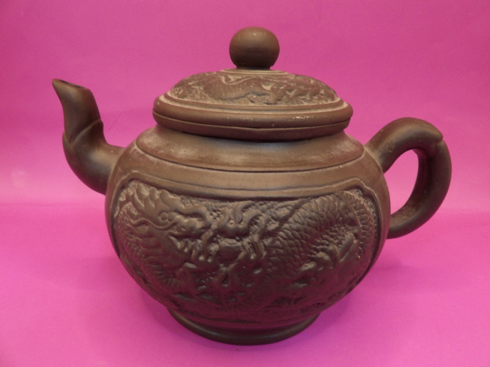 Chinese Yixing teapot with dragon motif and strainer signed: 7 inches length.