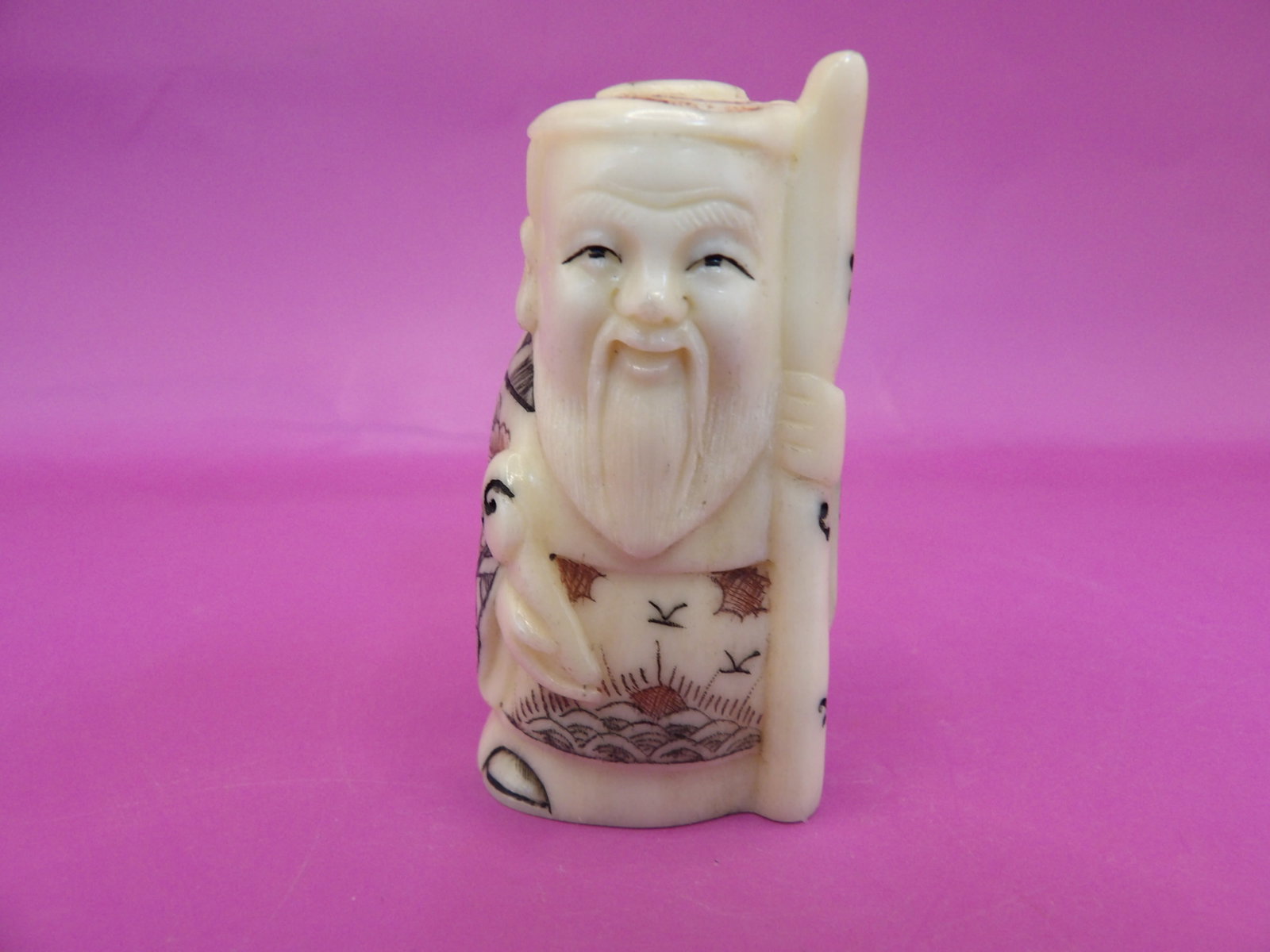antique Japanese carved bone netsuke depicting a deity holding a cane signed: 1.8 inches height.