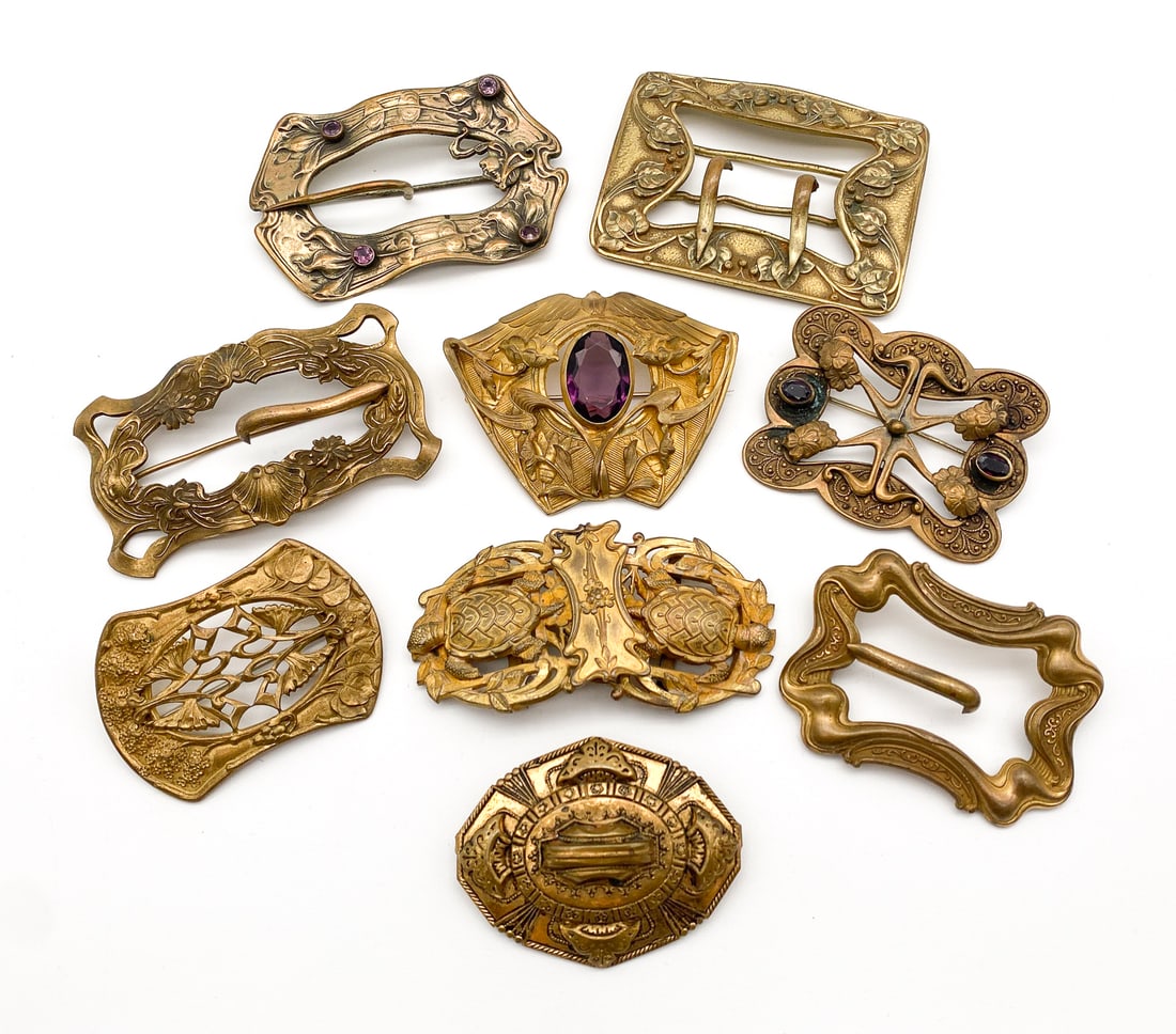 Nine Art Nouveau Brass Brooches & Buckles: Nine Art Nouveau Brass Brooches & Buckles, American And English, Late 19th Century, One Stamped Apollo Studios, New York, Two With Amethysts, One With Garnets, Largest 2.5 X 3.75 Inches, All With Rubb