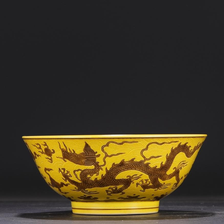 A large bowl with a deep belly with a yellow ground brown color carved seawater cloud dragon pattern: The Ming Dynasty Chenghua year yellow ground brown color carved seawater cloud dragon pattern deep belly bowl Size:H:8cmCalibre18.5cm (The Dimensions Of All Batches Are Manually