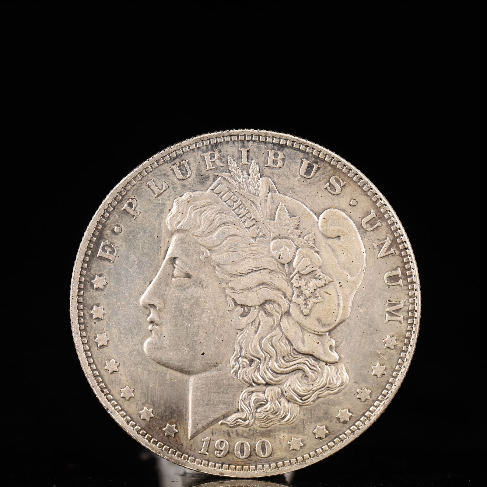 USA Morgan Dollar 1900 Coin: Obv: profile bust with date below and E PLURIBUS UNUM legend and stars around. Rev: eagle with In God we trust above within wreath with UNITED STATES OF AMERICA ONE DOLLAR legend. IN GOD WE TRUST / LI