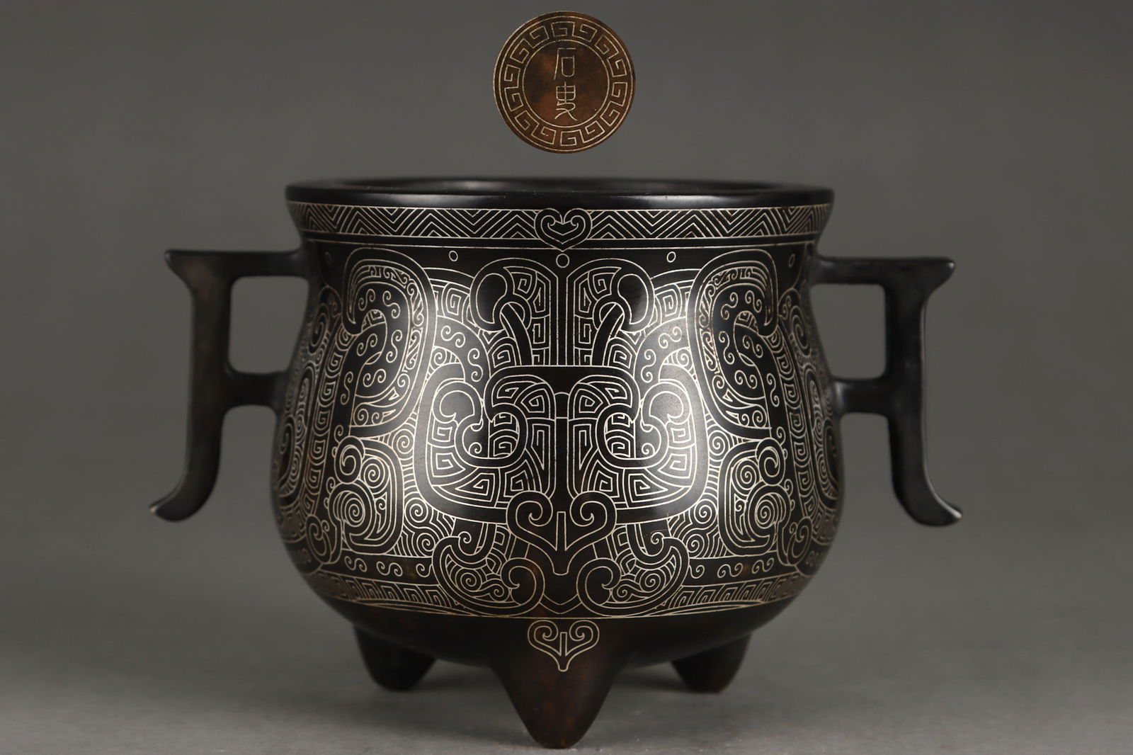 An Exquisite Bronze Inlaid Silver Beast-Face Pattern Double-Ears and Tripod Censer: An Exquisite Bronze Inlaid Silver Beast-Face Pattern Double-Ears and Tripod Censer Ming Dynasty, China Size:8.8cmx10.5cm Weight:1150g (The Dimensions Of All Batches Are Manually Measured.If You
