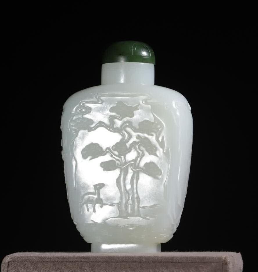 A Qing Dynasty Hetian jade snuff bottle: Qing Dynasty Hetian jade snuff bottle is flat and square, with jasper lid buttons, and the color is contrasting; A bas-relief picture of "Plum Wife and Crane", the pine trees are vigorous, the charact