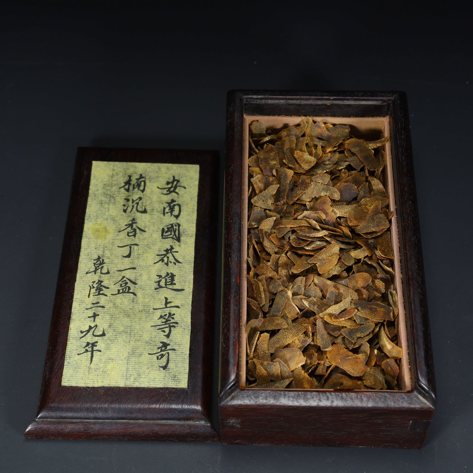 A piece of Qinan agarwood slices that was paid tribute by the Annan Kingdom in the twenty-ninth year: Qinan agarwood tablets paid tribute to the Annan Kingdom in the twenty-ninth year of Qianlong SIZE: Box H: 5.2cm L: 15cm W: 8cm Total W: 317.6g Agarwood Clove W: 39.5g (The Dimensions Of All Batches A