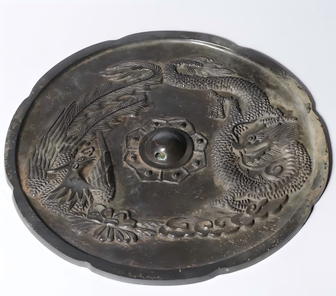 A Tang Dynasty bronze dragon and phoenix auspicious mirror: Tang Dynasty Bronze Dragon and Phoenix Presenting Auspicious Mirror This bronze mirror is regular in shape, cast in bronze, excellent in pulp, simple in shape, dignified in shape, round, bead button,