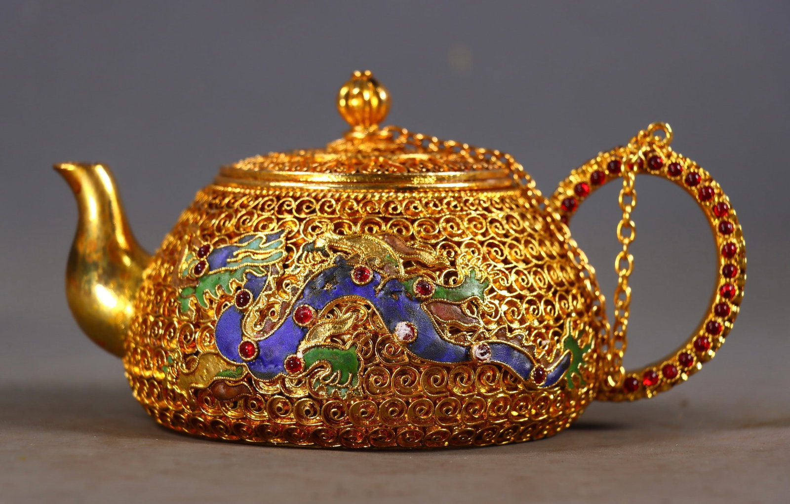 An Exquisite Gilt Bronze Inlaid Gems Dragon and Phoenix Pattern Teapot: An Exquisite Gilt Bronze Inlaid Gems Dragon and Phoenix Pattern Teapot Qing Dynasty, China Qianlong Four-character Mark Size:8.5cmx14.5cmx9.5cm Weight:517g (The Dimensions Of All Batches Are Manually