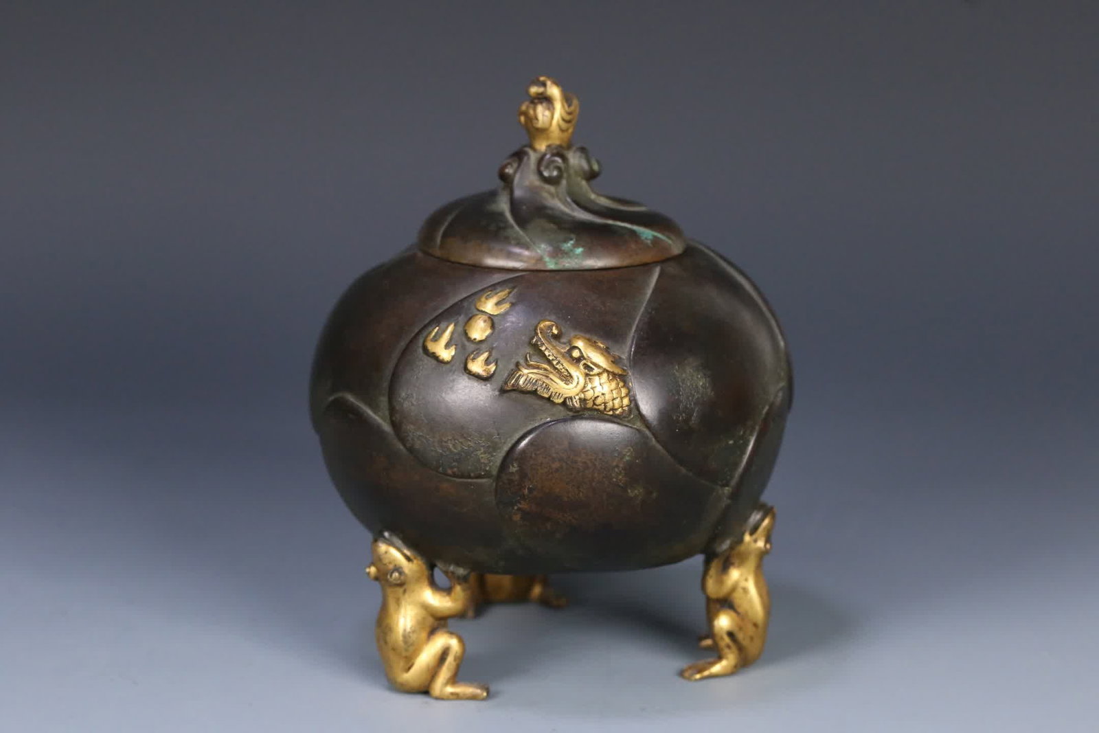 One is a Kangxi period gilt bronze incense burner with three frog feet and dragon motifs and petal: Kangxi-era model bronze gilt three-frog foot dragon pattern petal incense burner SIZE: 11.8x9.5cm W:560.4g (The Dimensions Of All Batches Are Manually Measured.If You Need More Detailed Information, P