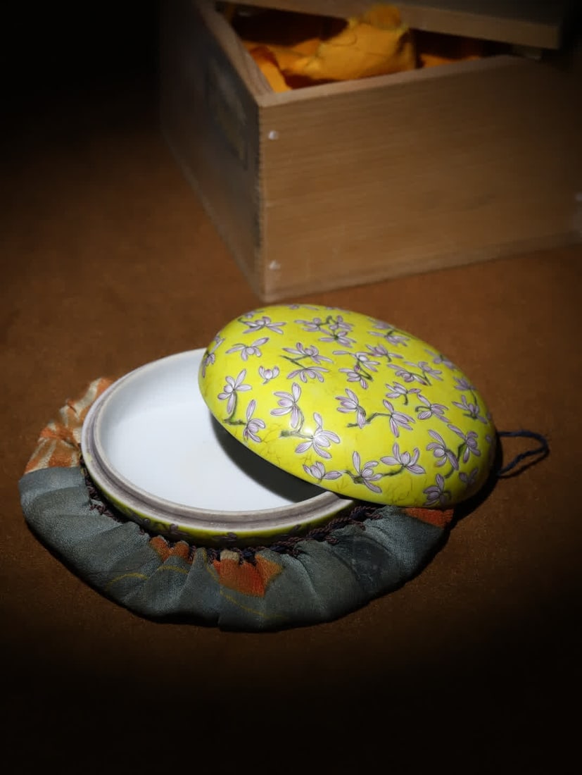 A Qing Dynasty Tongzhi period yellow ground famille rose magnolia pattern lid box: Qing Dynasty Tongzhi Yellow Ground Famille Rose Magnolia Pattern Lid Box: Made in the Tongzhi period of the Qing Dynasty in Japan, featuring an original old wooden box and the Gulong Society label,