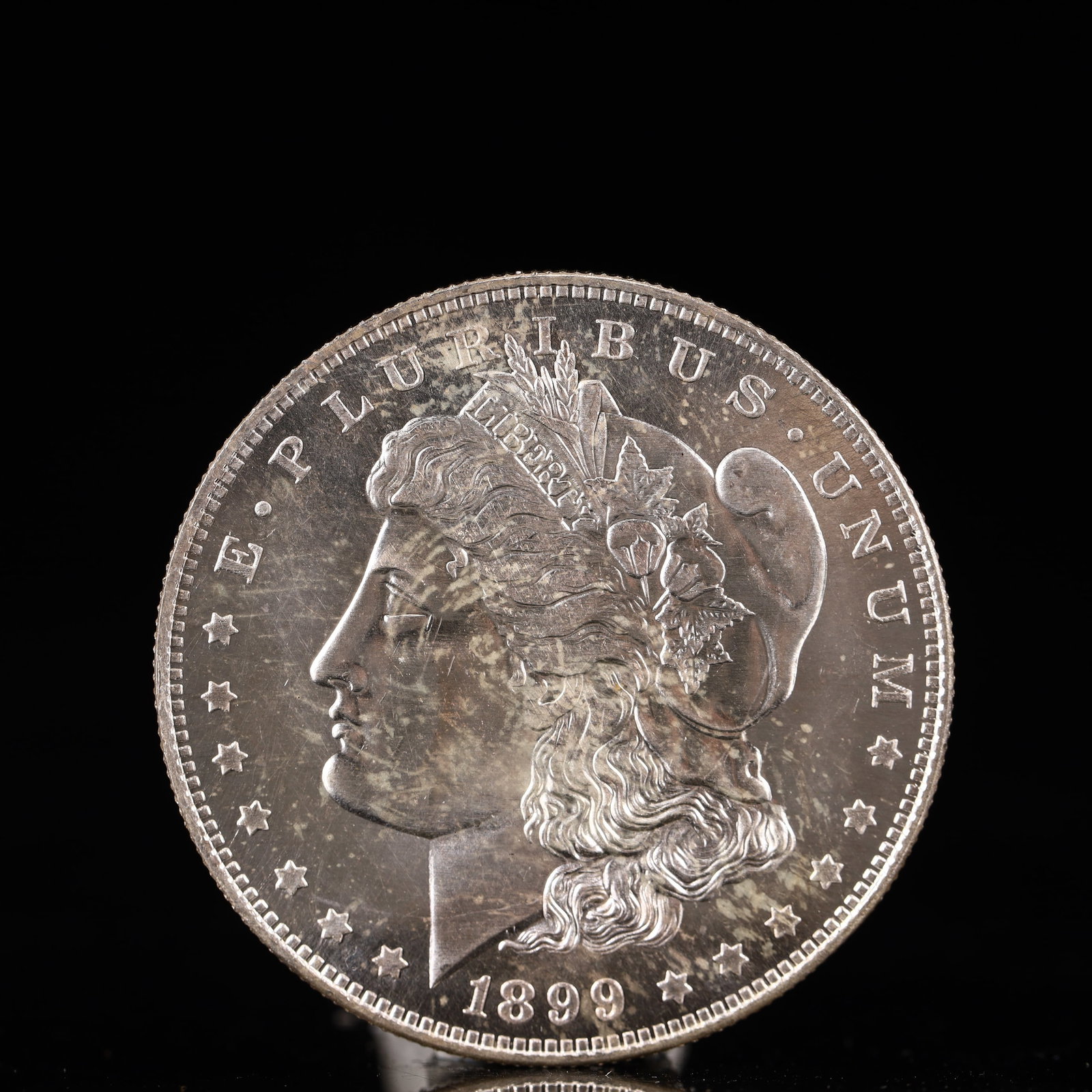 USA Morgan Dollar 1899 Coin: Obv: profile bust with date below and E PLURIBUS UNUM legend and stars around. Rev: eagle with In God we trust above within wreath with UNITED STATES OF AMERICA ONE DOLLAR legend. IN GOD WE TRUST /