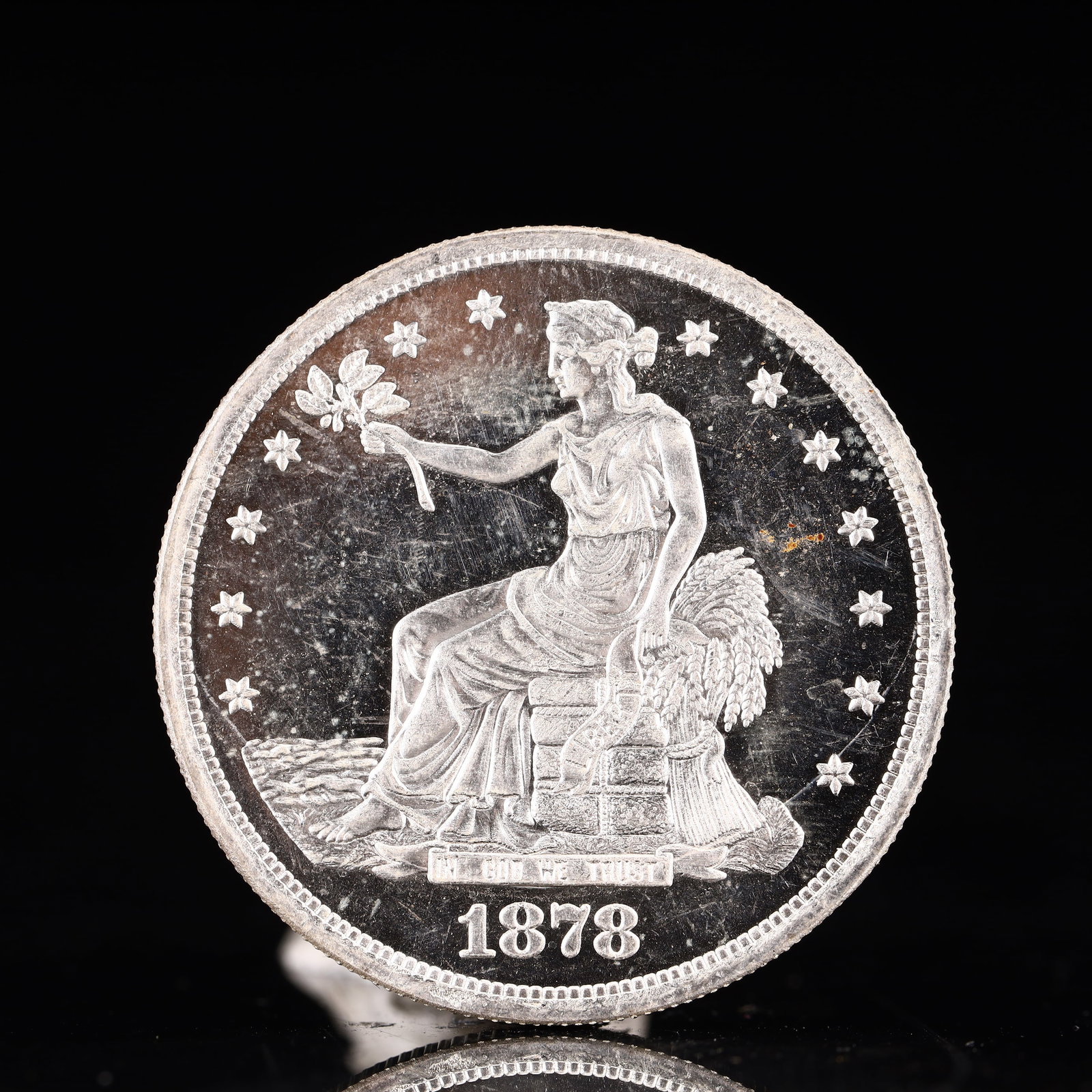 USA Trade Dollar 1878 Coin: American coin. Obverse: Liberty seated on a pedestal facing the sea to the left holding olive branches surrounded by 13 stars. IN GOD WE TRUST / LIBERTY / 1878. Reverse: An eagle holding branches with