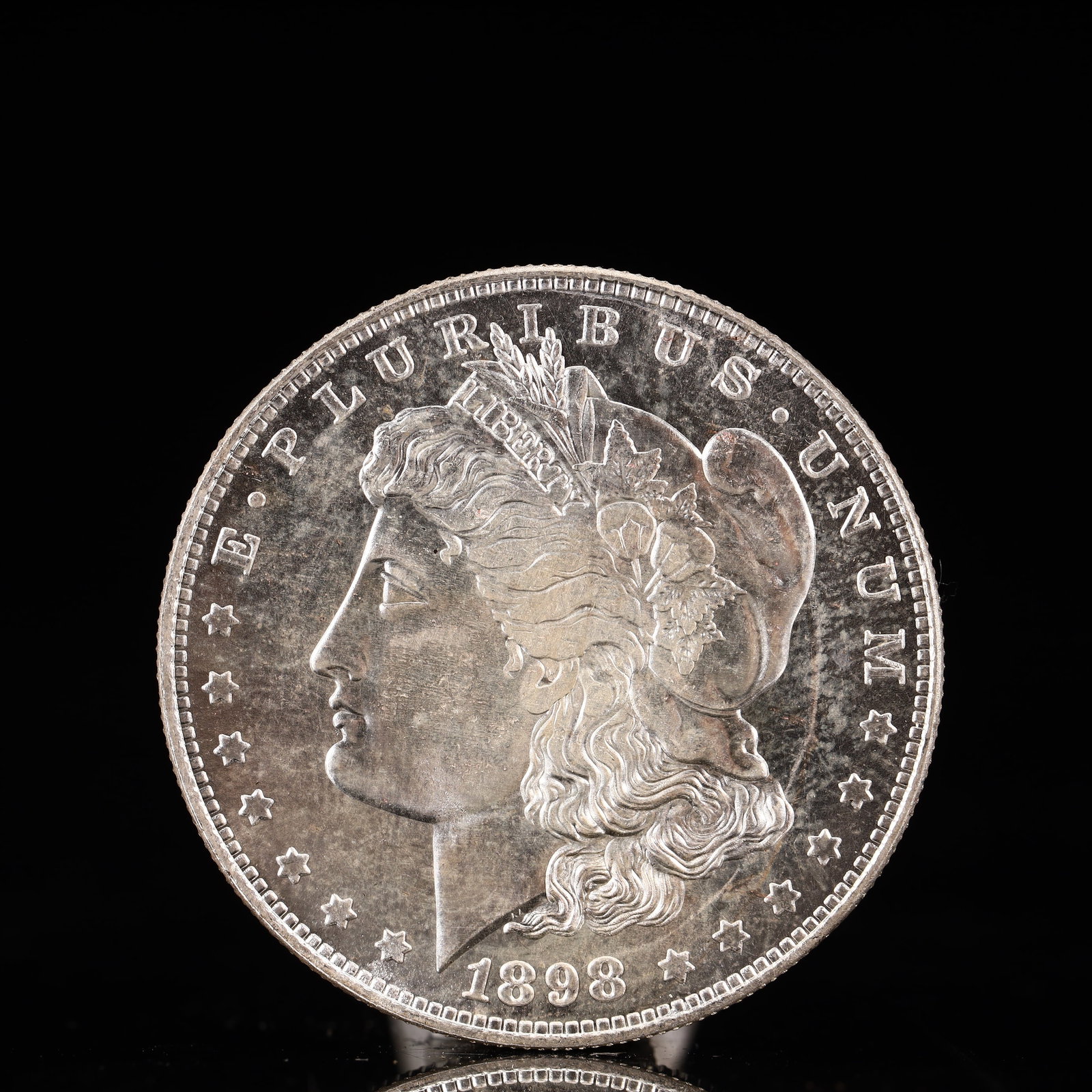 USA Morgan Dollar 1898 Coin: Obv: profile bust with date below and E PLURIBUS UNUM legend and stars around. Rev: eagle with In God we trust above within wreath with UNITED STATES OF AMERICA ONE DOLLAR legend. IN GOD WE TRUST / LI