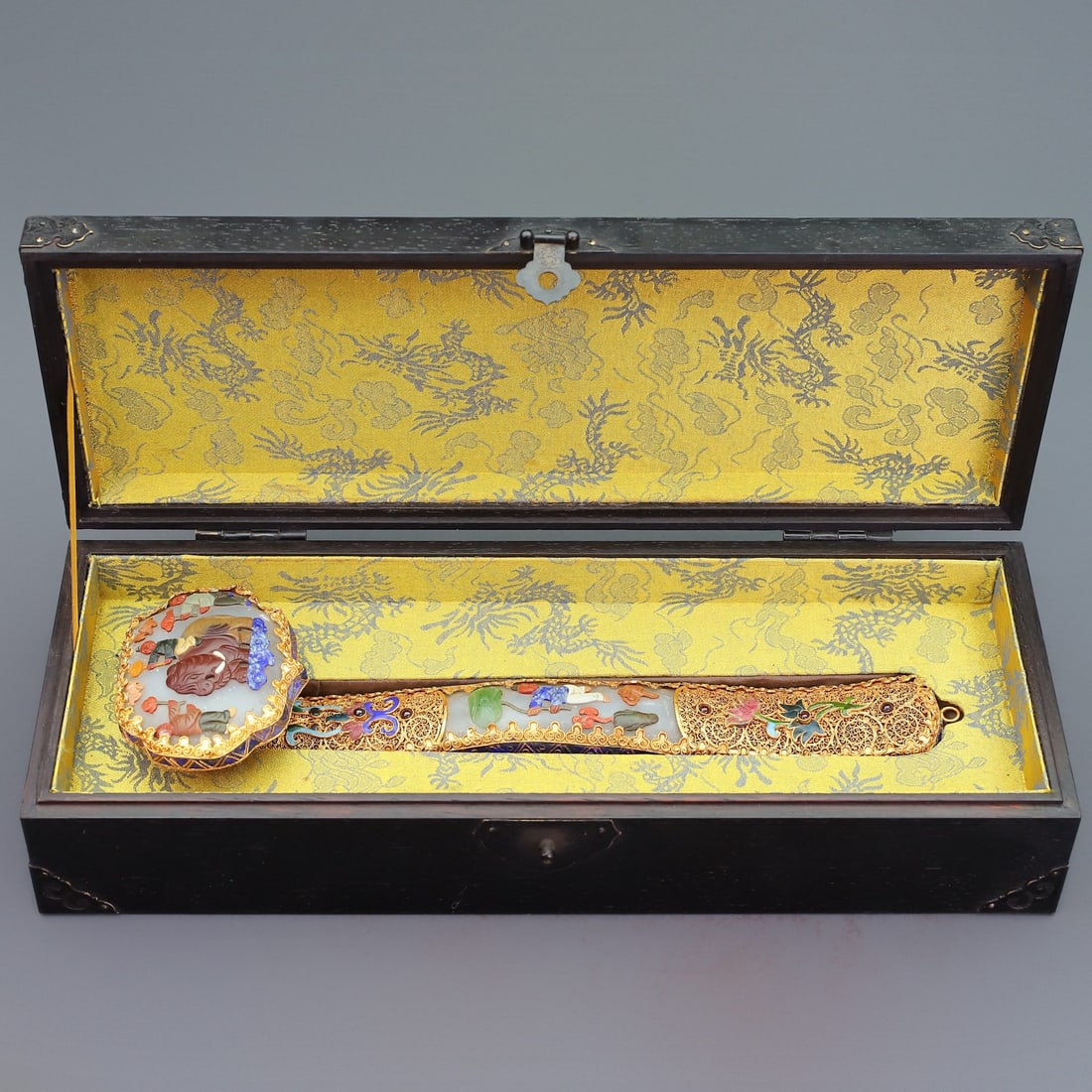 An Exquisite Gilt Bronze Inlaid Gems Character and Story Pattern Ruyi: An Exquisite Gilt Bronze Inlaid Gems Character and Story Pattern Ruyi Qing Dynasty, China Qianlong Four-character Mark Size:32.5cmx9cm Weight:660g Size:10cmx38.5cmx14.5cm Weight:1260g (The Dimensions