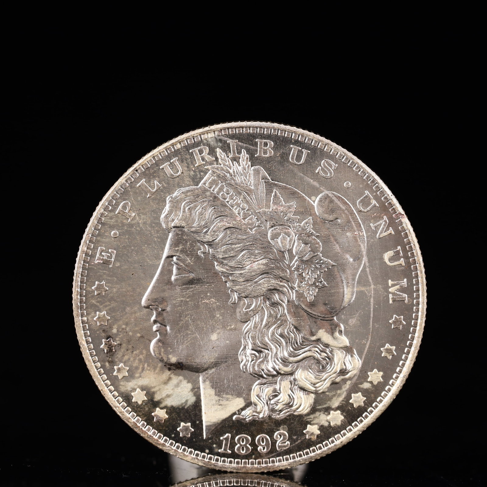 USA Morgan Dollar 1892 Coin: Obv: profile bust with date below and E PLURIBUS UNUM legend and stars around. Rev: eagle with In God we trust above within wreath with UNITED STATES OF AMERICA ONE DOLLAR legend. IN GOD WE TRUST / LI