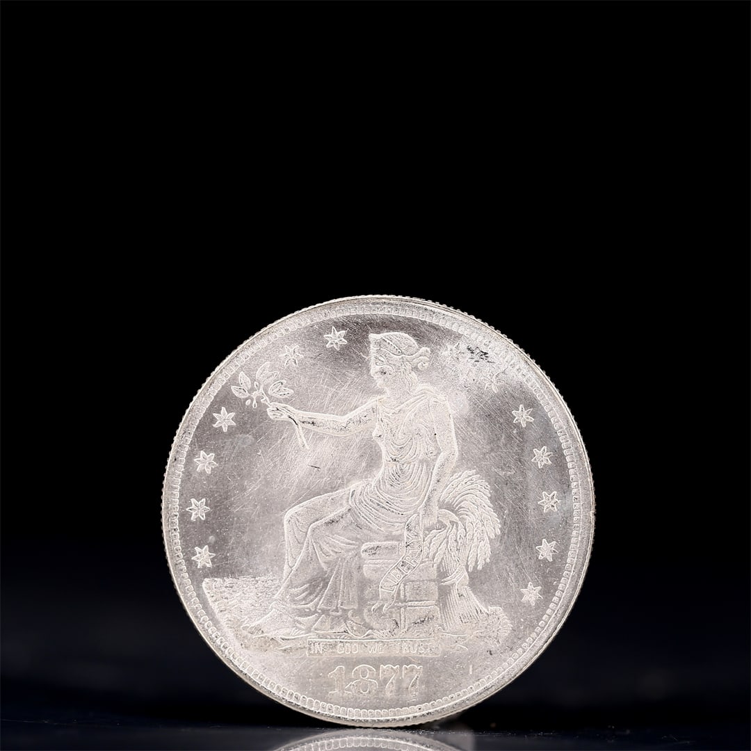 USA Trade Dollar 1877 Coin: American coin. Obverse: Liberty seated on a pedestal facing the sea to the left holding olive branches surrounded by 13 stars. IN GOD WE TRUST / LIBERTY / 1877. Reverse: An eagle holding branches