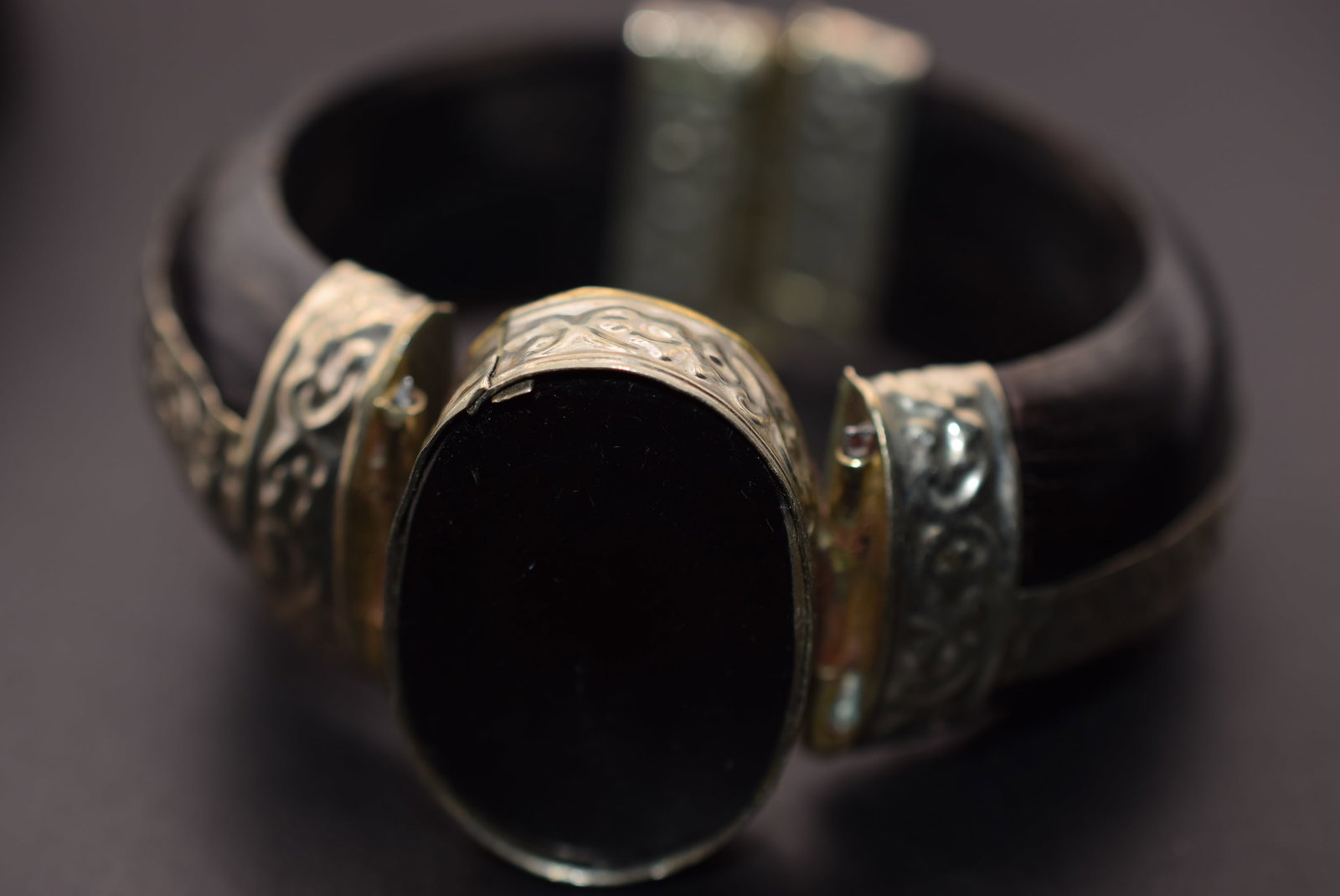 Huge Hinged Bangle Bracelet Onyx Center Lot 35: Huge Hinged Bangle Bracelet Onyx Center opening measures 2 3/8" across and is 1" wide appears to be made of wood with the line inside indicating two pieces they put together to make it a wide bracelet