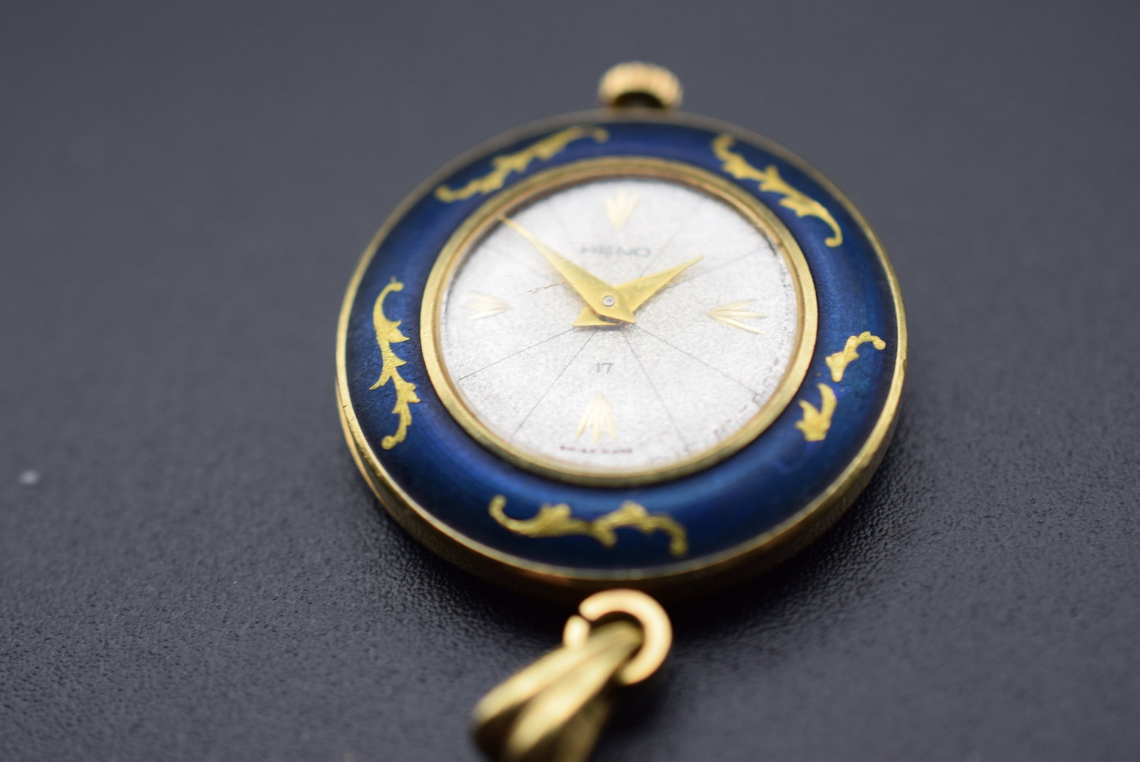 Heno Vintage 1940's Enamel Pendant Watch Lot 587: Heno Vintage 1940's Enamel Pendant Watch measures 1" in diameter plus the bale signed Heno Swiss 17 Jewel Heno Interlaken D 3423 unadjusted movement moves but doesn’t keep time