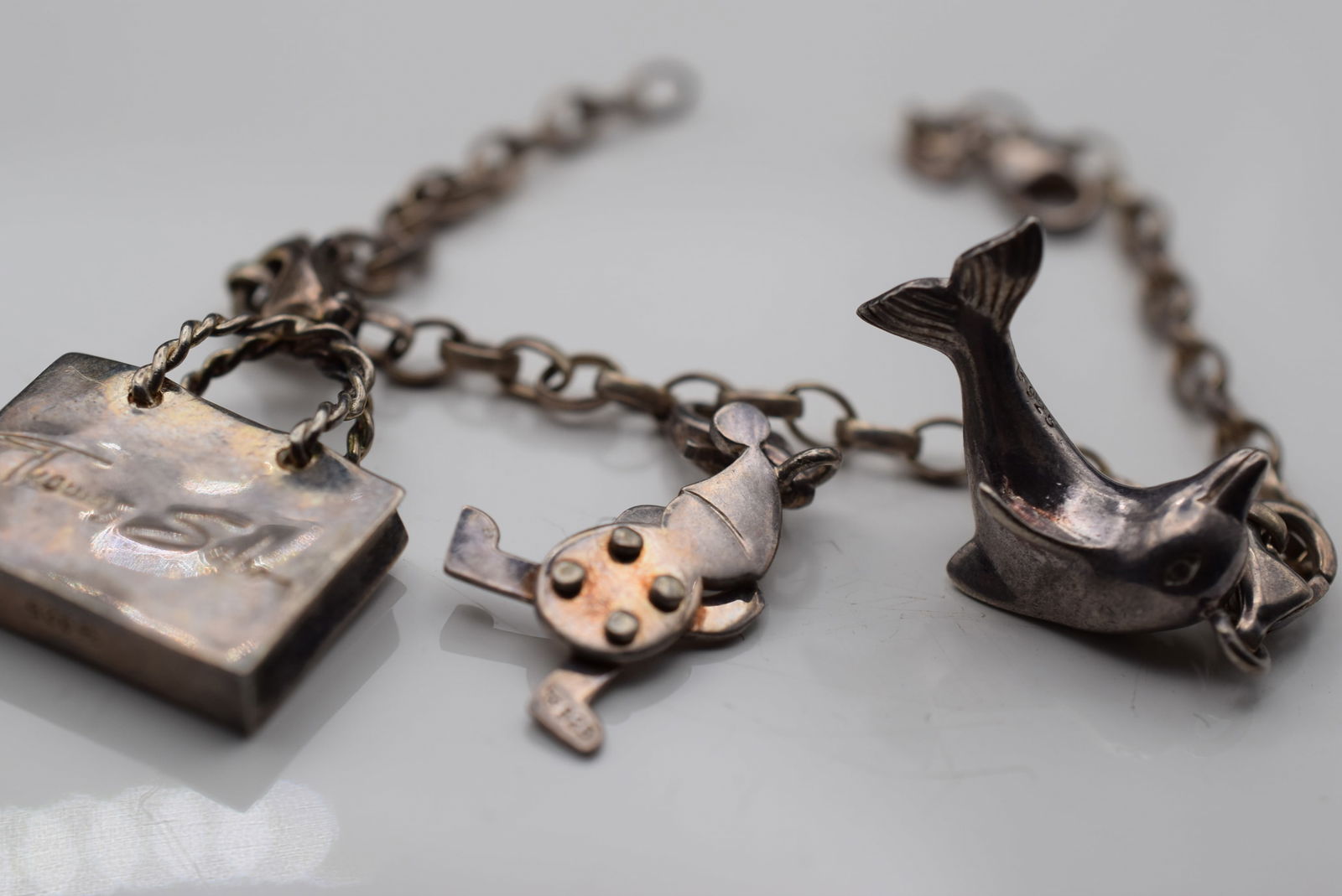 Thomas Sabo Sterling Silver 925 Bracelet with 3 Charms all Signed Lot EH 887: Thomas Sabo Sterling Silver 925 Bracelet with 3 Charms all Signed Thomas Sabo The purse signed Thomas Sabo Shopping Victim the Dolphin and moveable Elf all signed Thomas Sabo the arms and legs of the